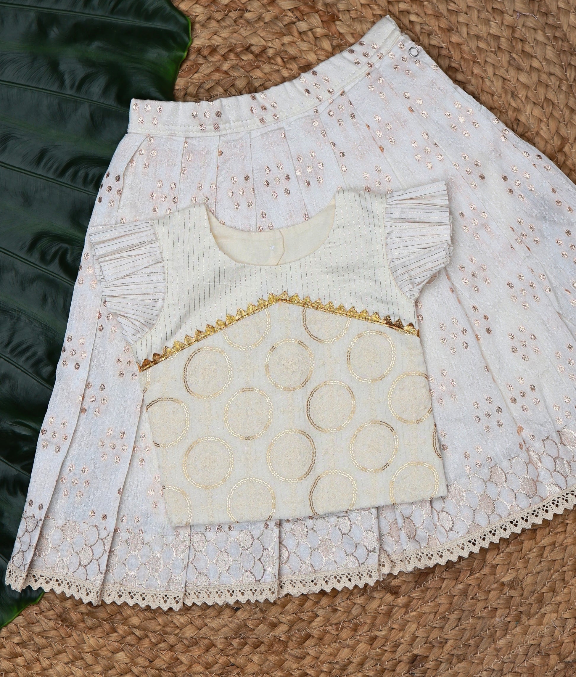 White lace skirt and top on a leaf and a woven mat background.