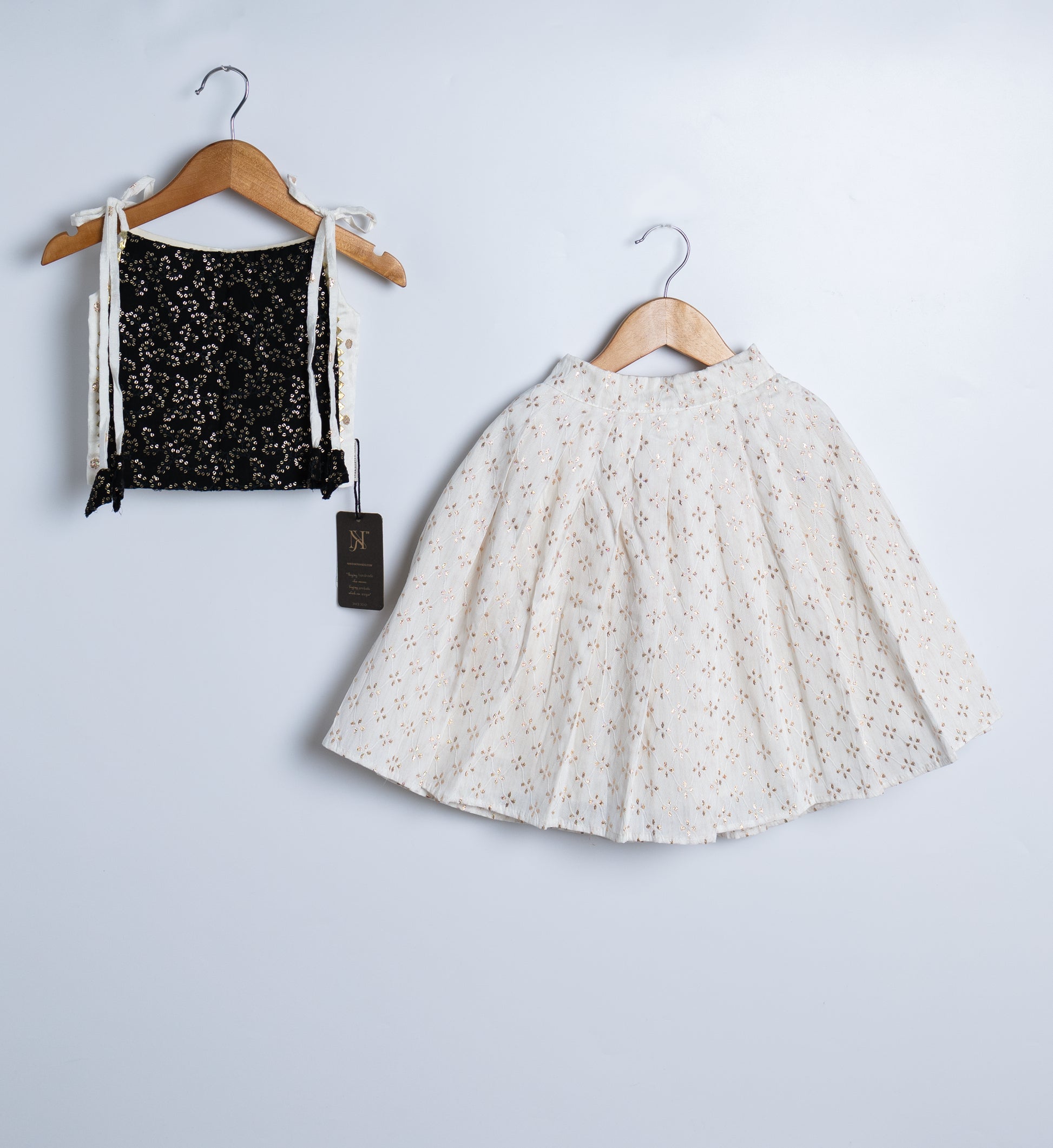A black georgette crop top and a chanderi skirt displayed on hangers against a white background.