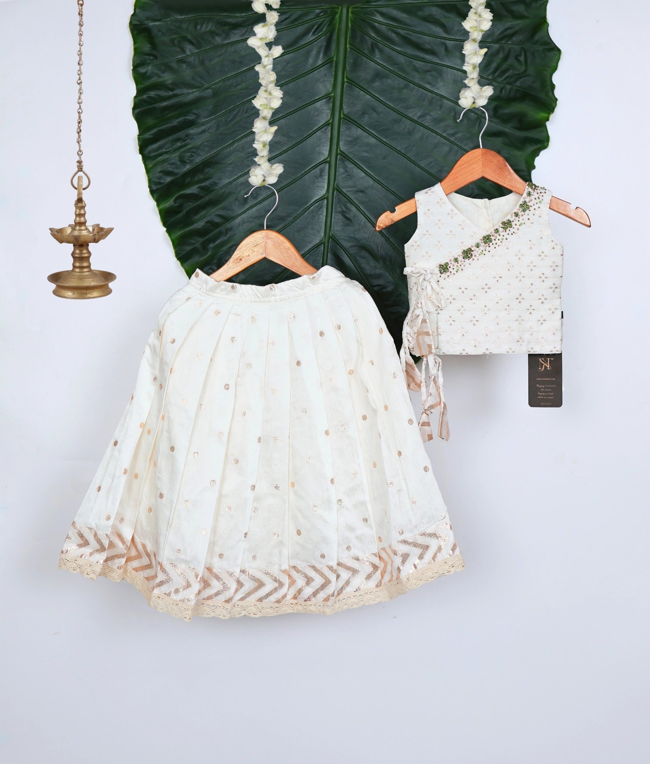 Off-white outfit with a hanger displayed on a leaf and a white background.