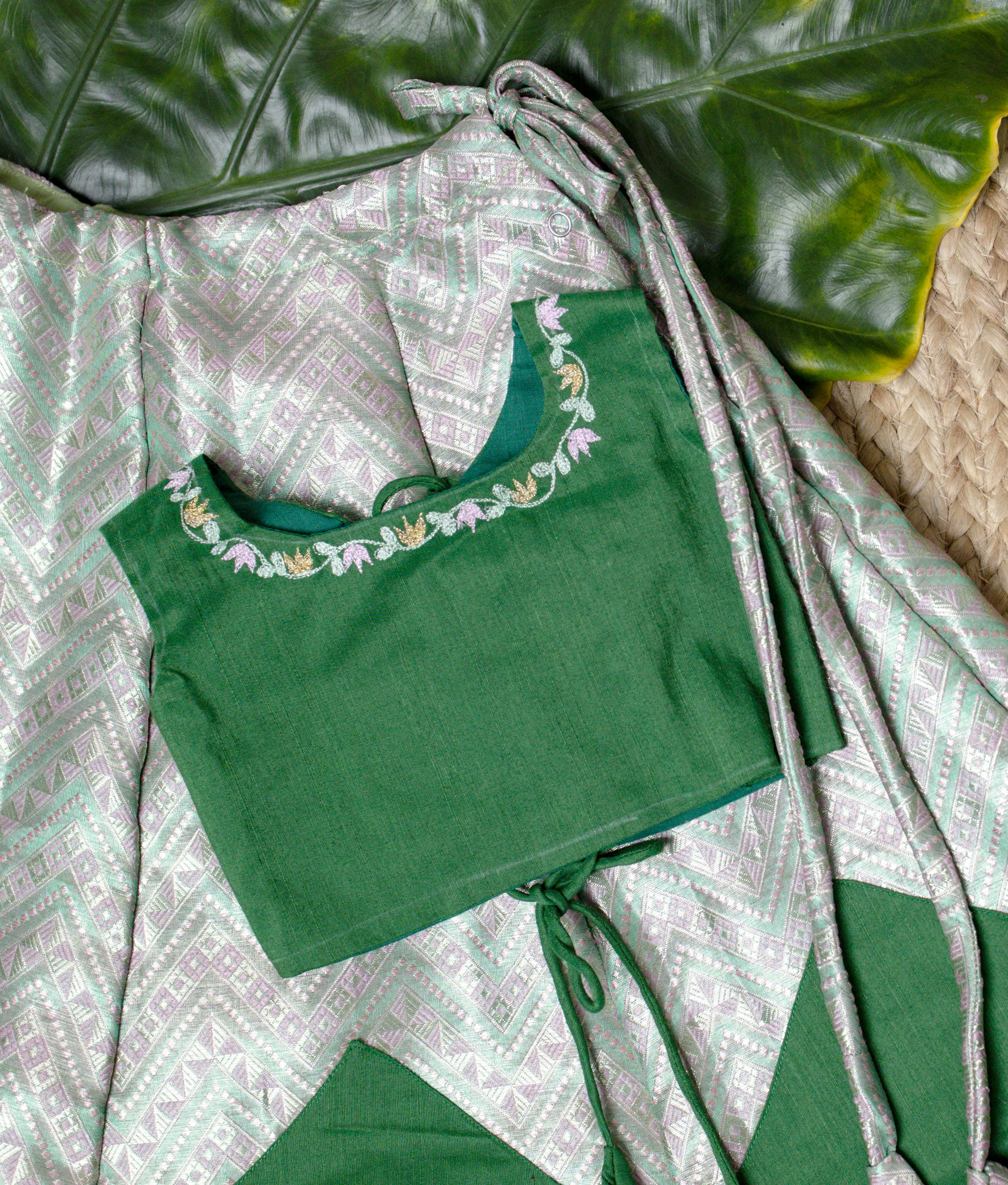 Stylish green kids set with embroidered sleeveless blouse and chevron-patterned skirt, displayed on wooden hangers against leaf background