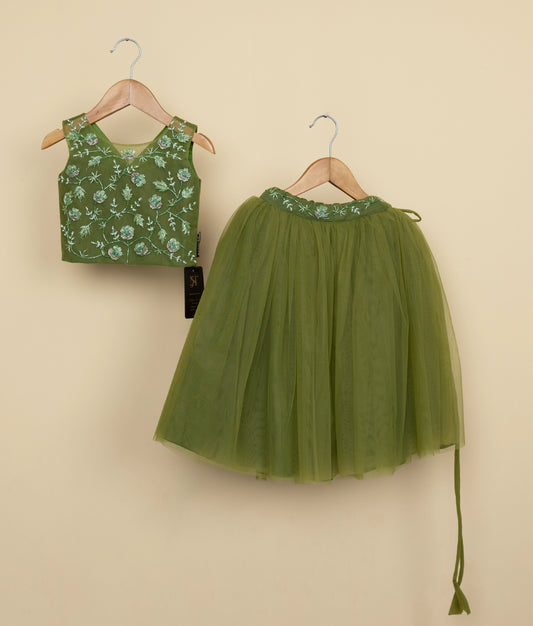 Olive Green floral tulle net top and skirt on hangers against a beige wall background.