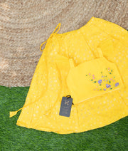 Yellow floral embroidered top with a matching yellow Georgetta skirt laid out on a green surface.