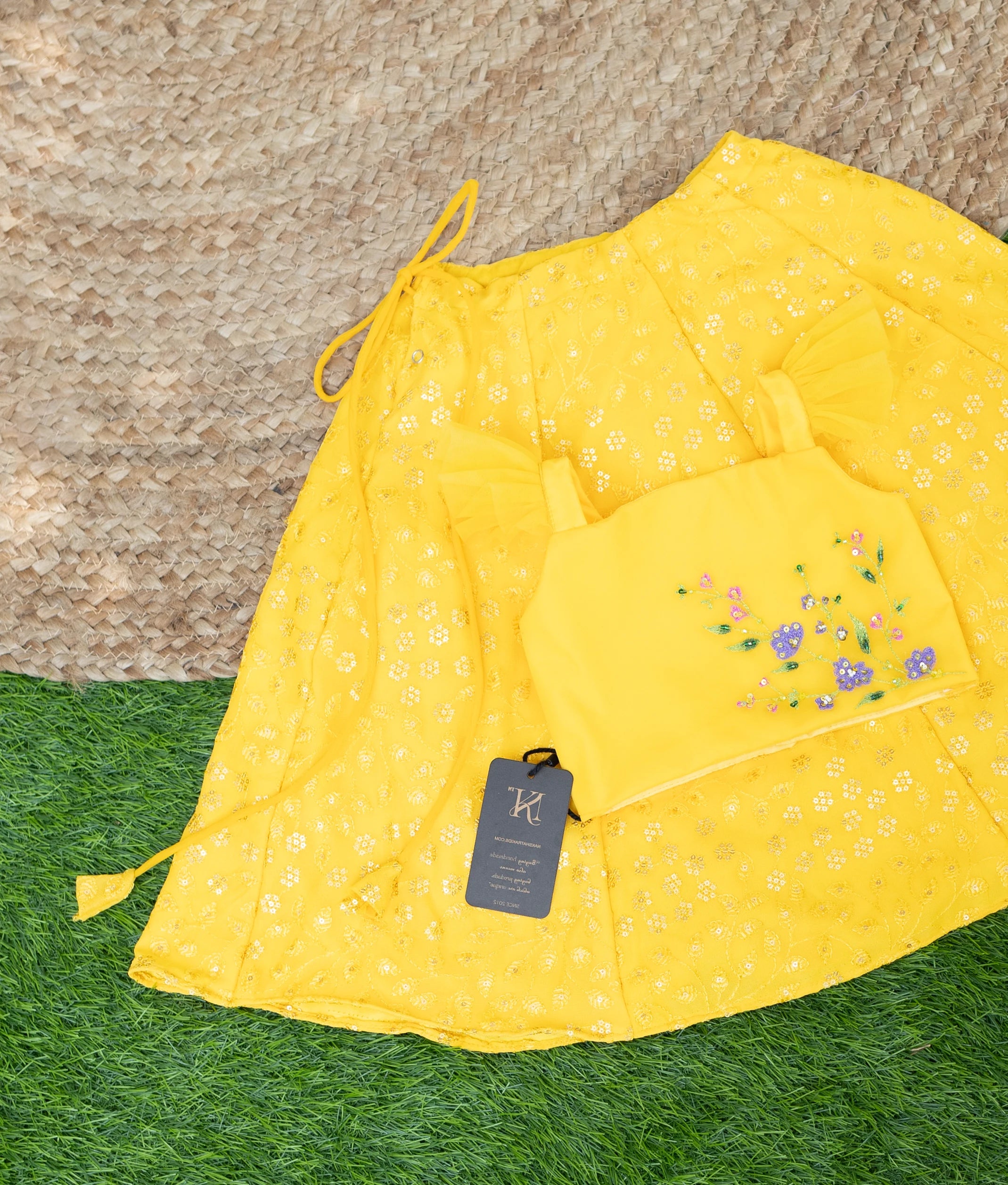 Yellow floral embroidered top with a matching yellow Georgetta skirt laid out on a green surface.