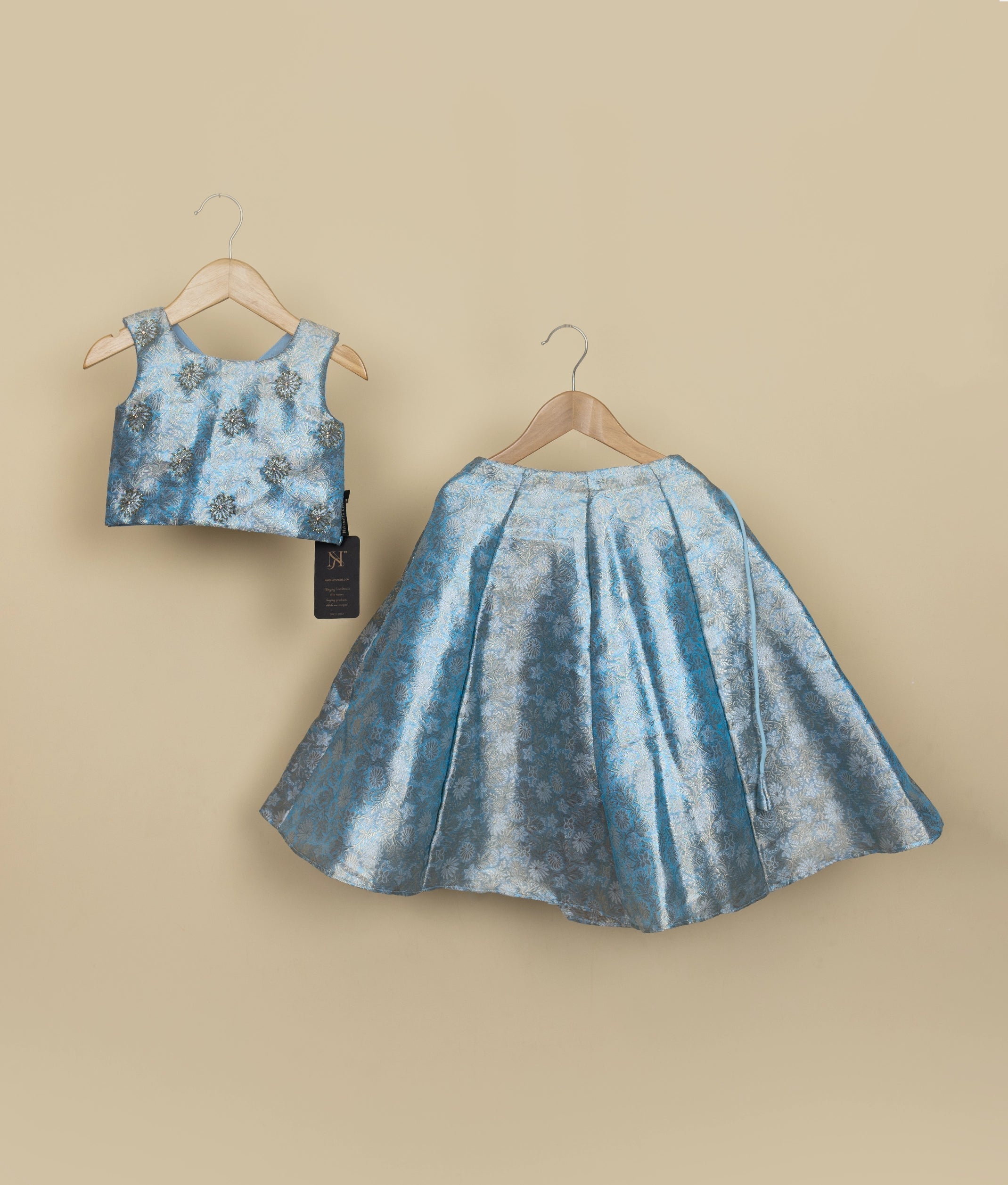 A sky blue Banarasi top and skirt set on hangers against a beige background.