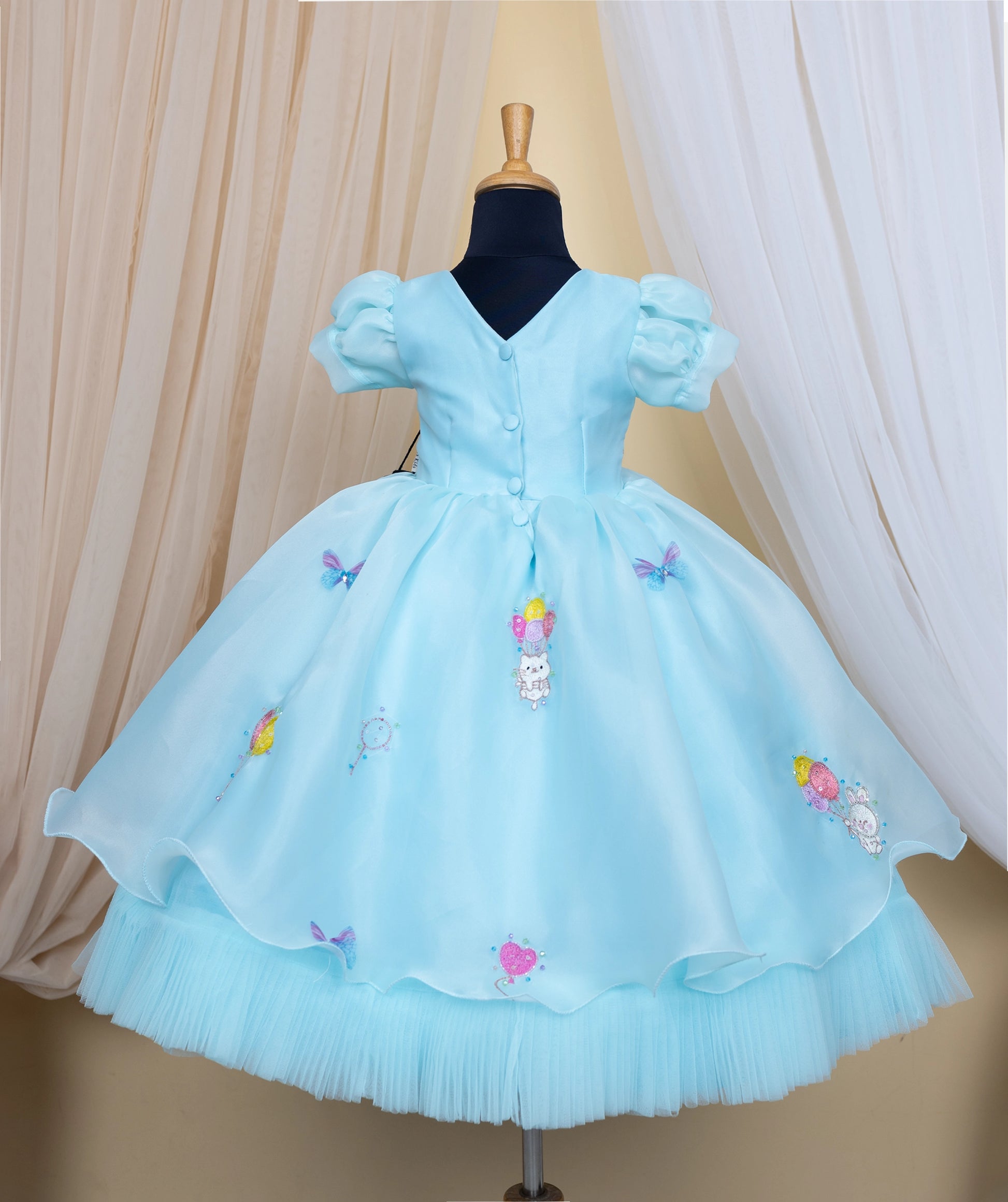 Back view of an sky blue frock with baloon theme on a mannequin against a neutral background.