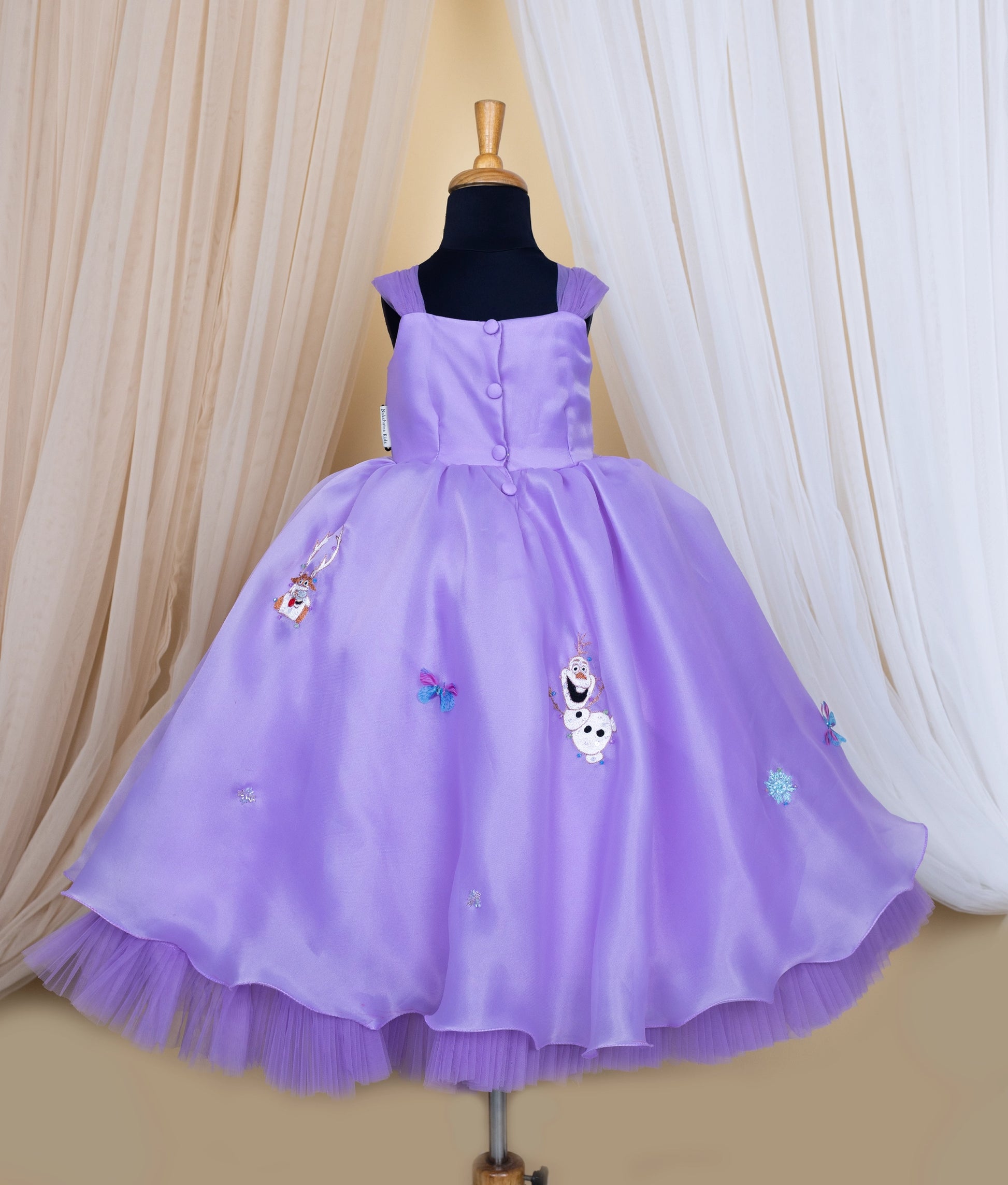 Back view of lavender elsa theme with character embroidery on a mannequin against a beige curtain background.