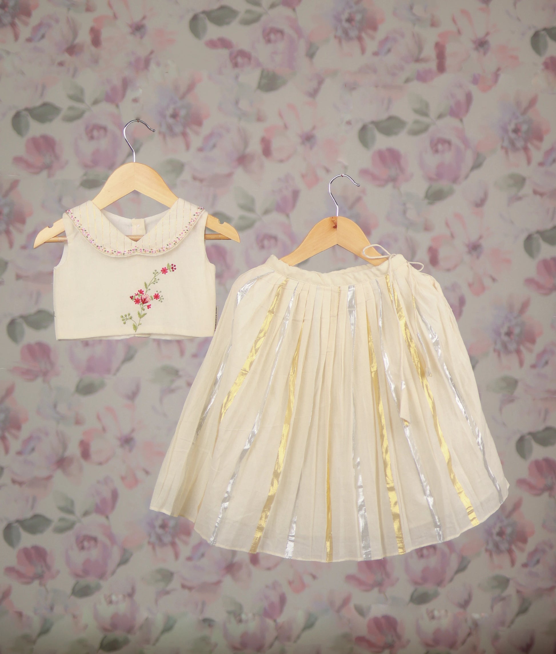 off-white baby girl's festive skirt set with a floral embroidery top and a golden Kasav line skirt.
