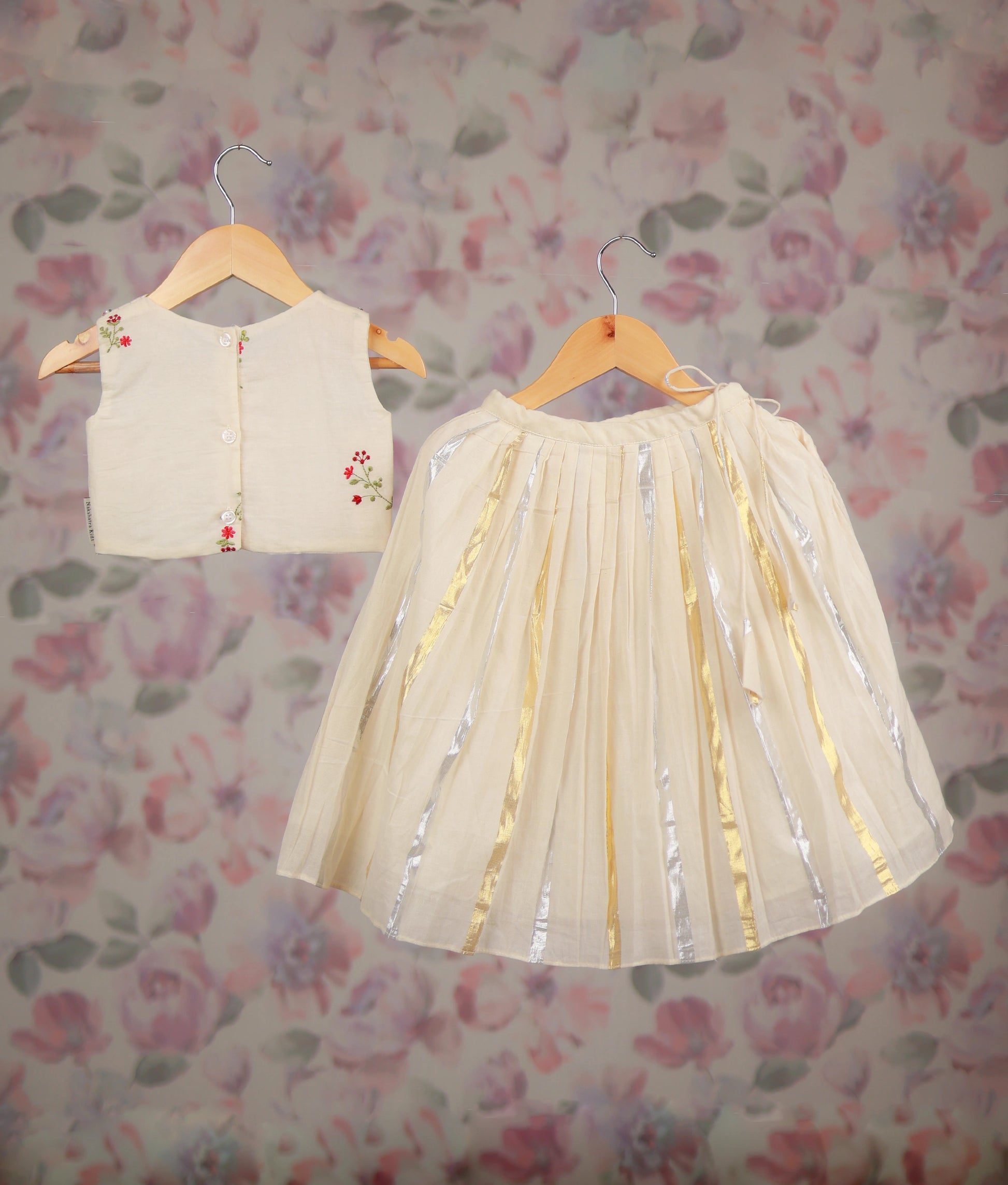 Back view of an off-white baby girl's festive skirt set with a floral embroidery top and a golden Kasav line skirt.