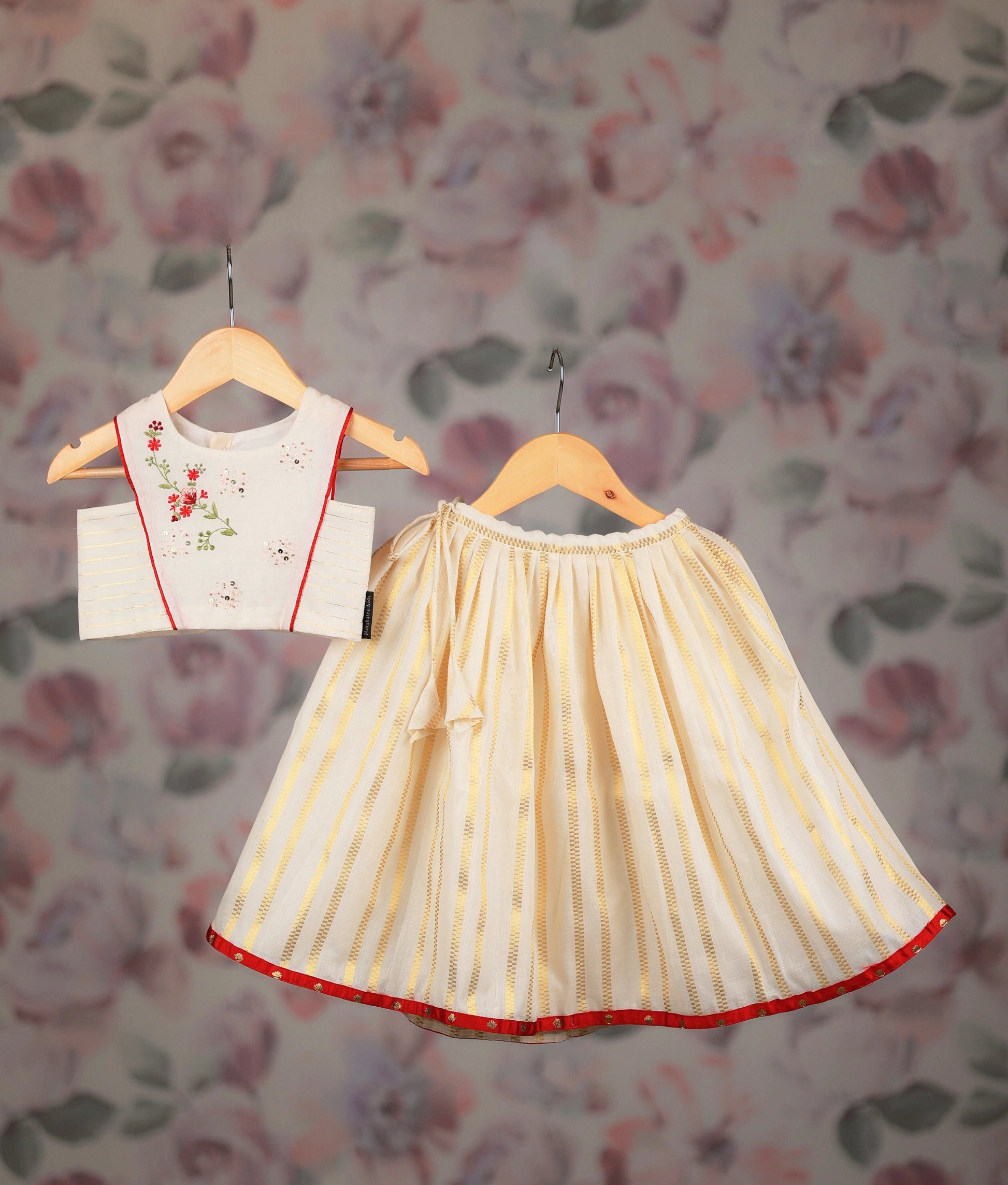 Off-white and golden baby girl skirt with embroidery top, displayed on a hangers.