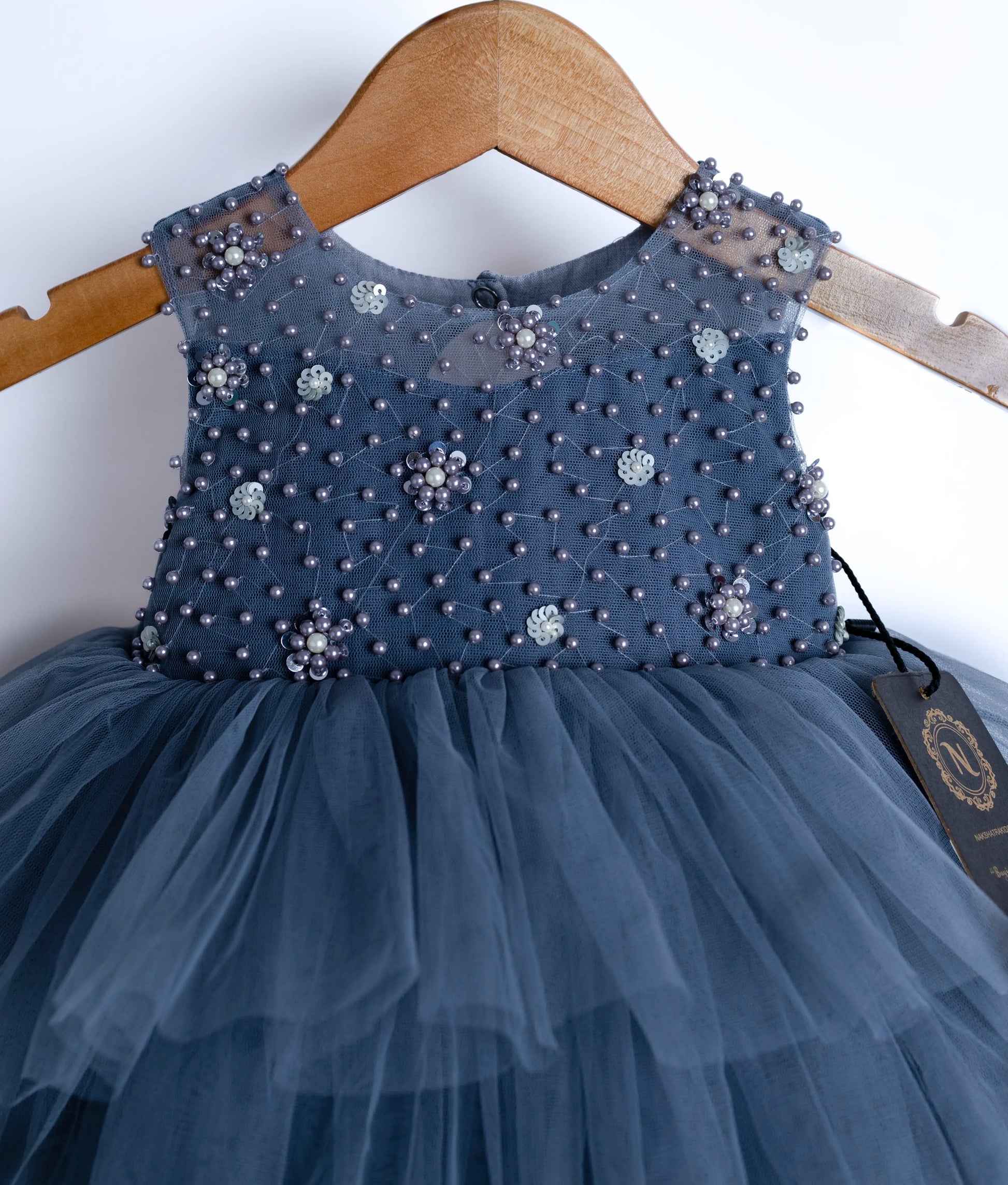 Close view of an sleeveless, ash gray tulle net frock displayed on a hanger.