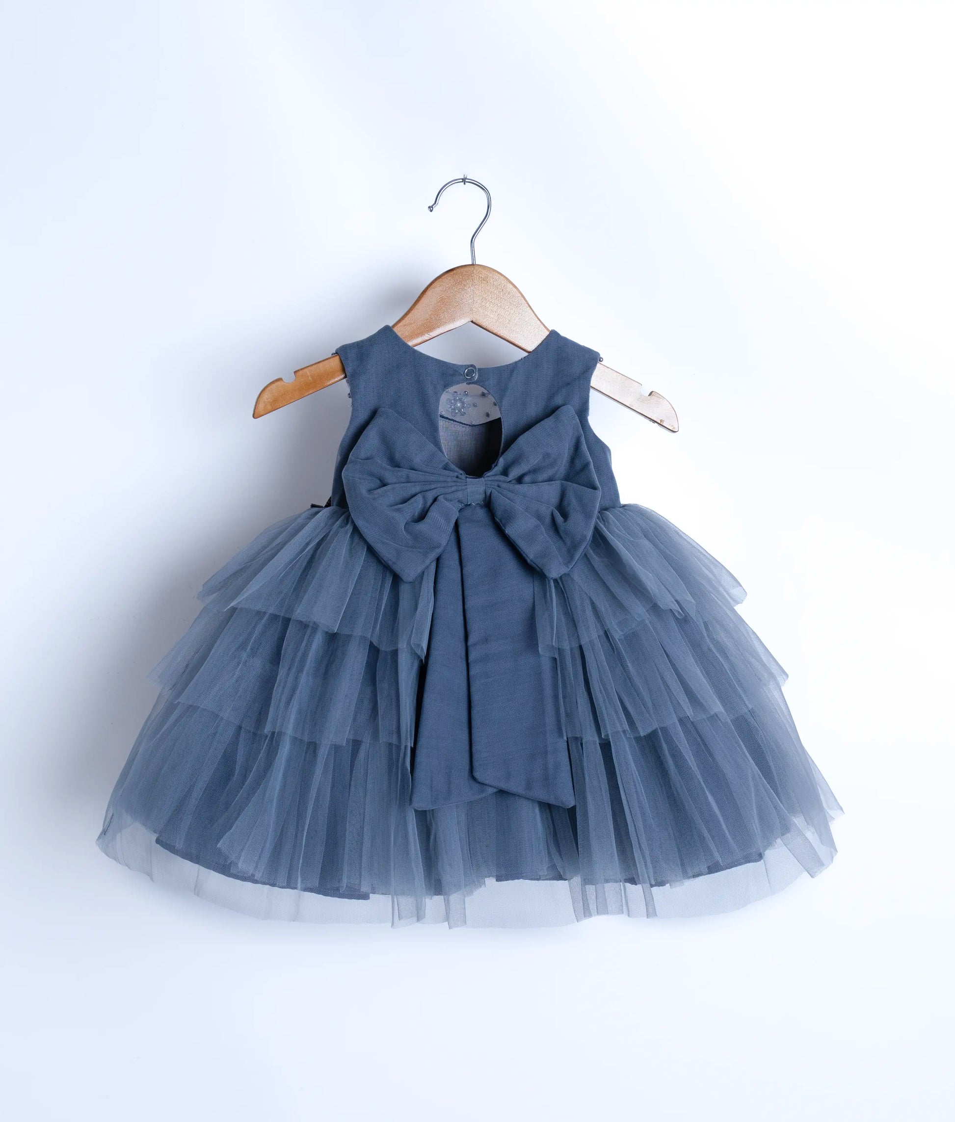 Back view of an sleeveless, ash gray tulle net frock displayed on a hanger.