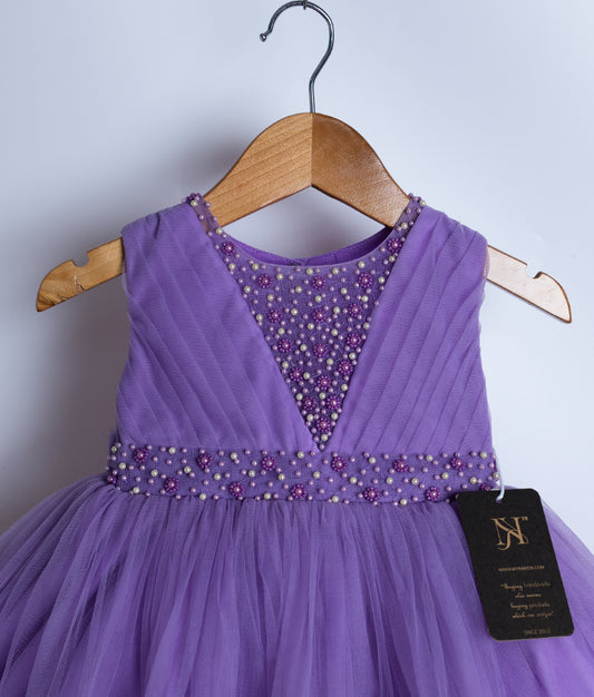 Close view of an sleeveless lavender party frock displayed on a wooden hanger.