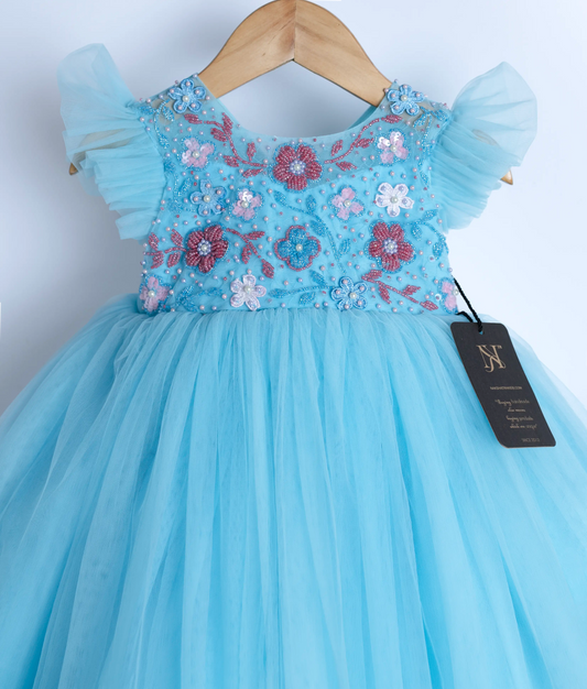 Close view of an blue tulle net frock displayed on a hanger.