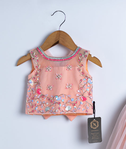 A peach top is displayed on hangers against a white background.