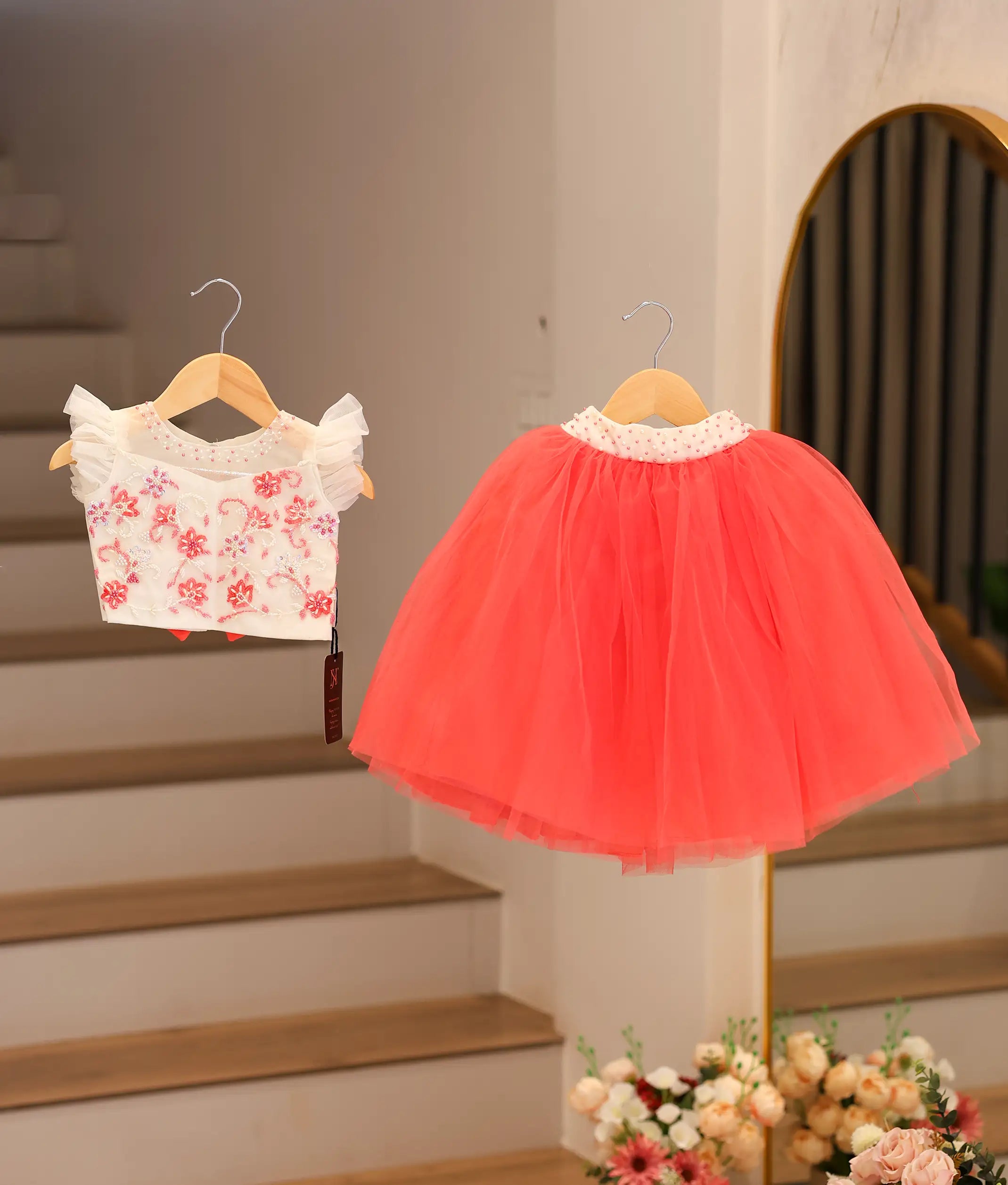 Front view of an off-white top with a dark pink skirt hanging.