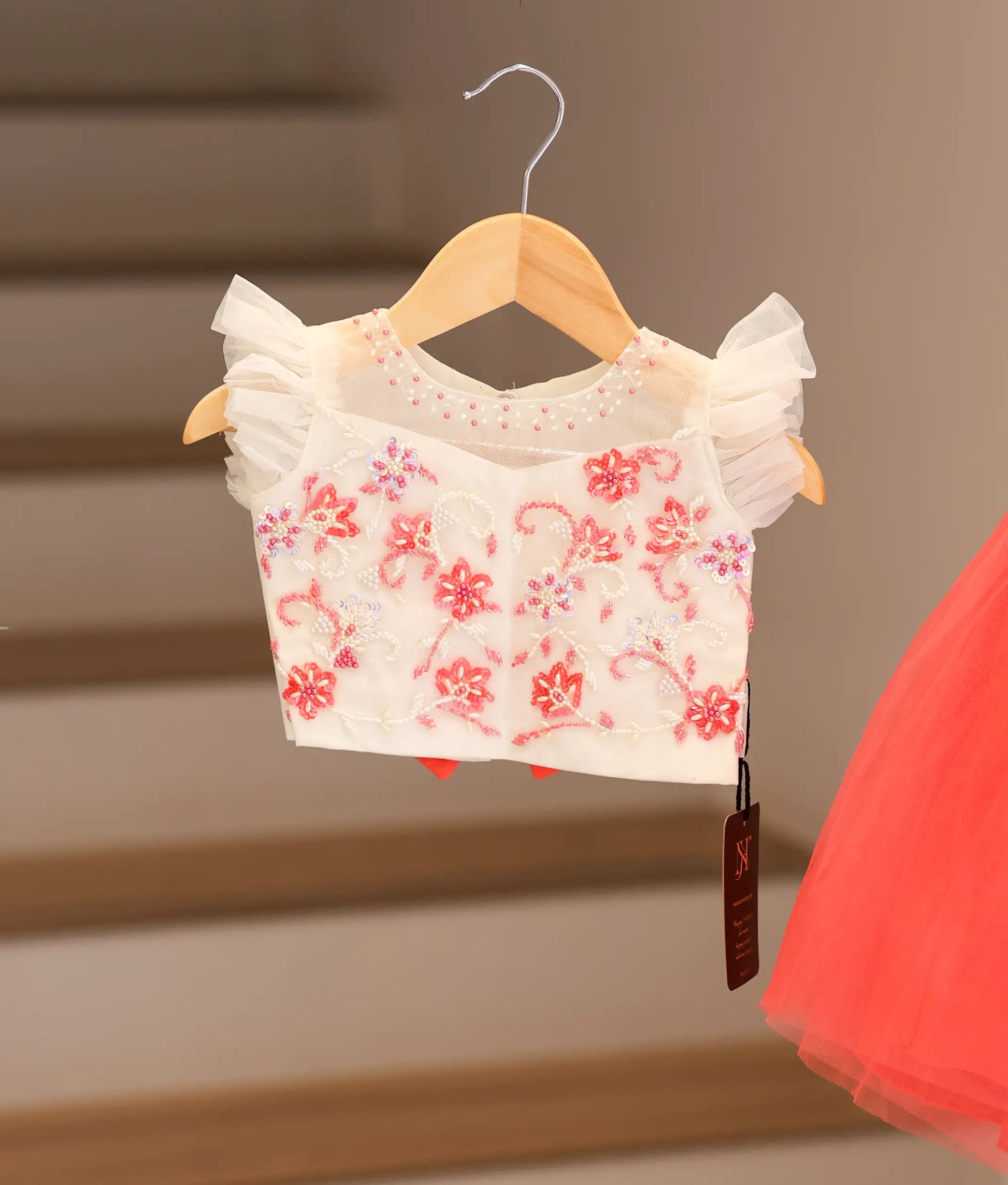Close view of an off-white top with a dark pink skirt hanging.