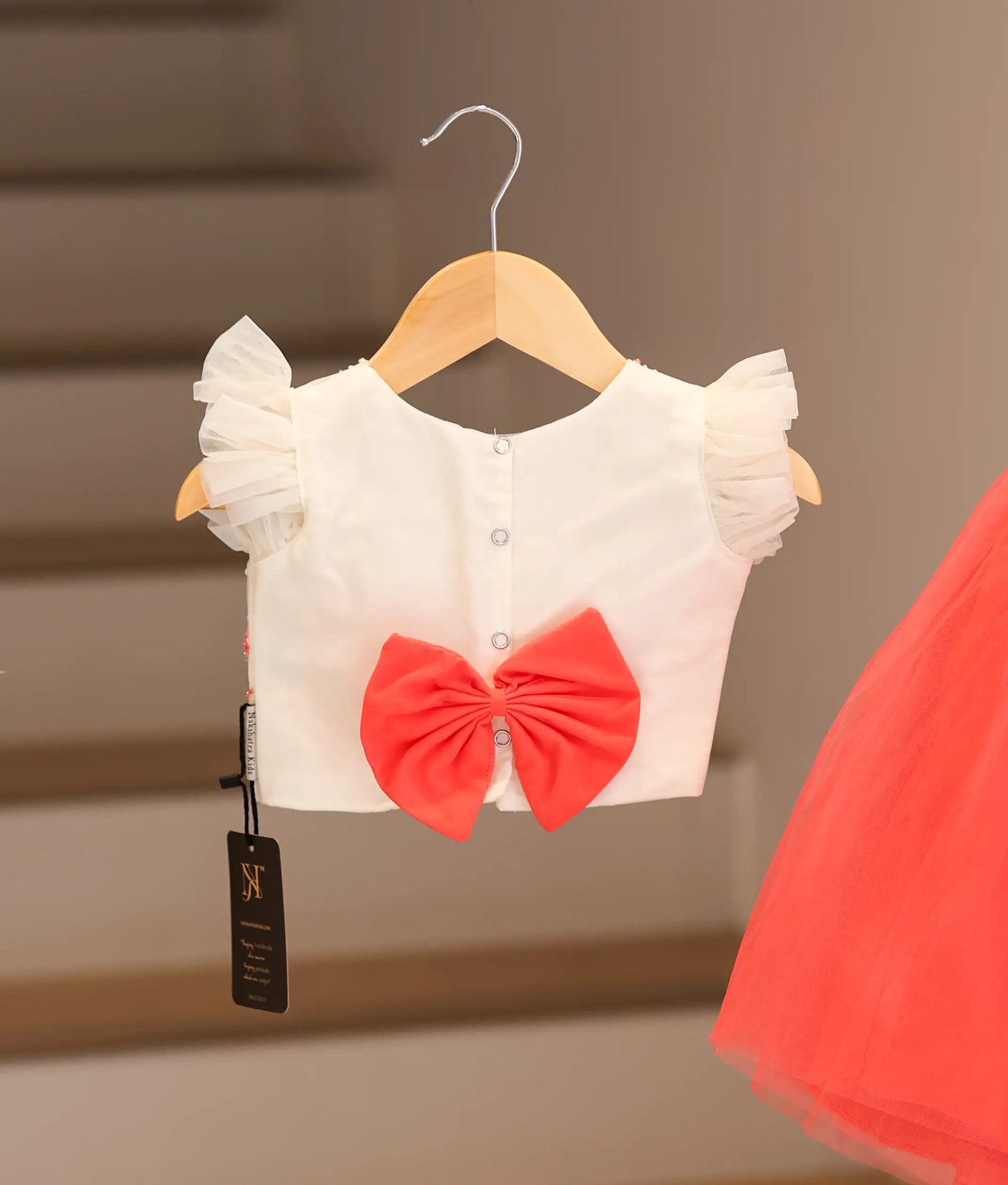 Back view of an off-white top with a dark pink skirt hanging.