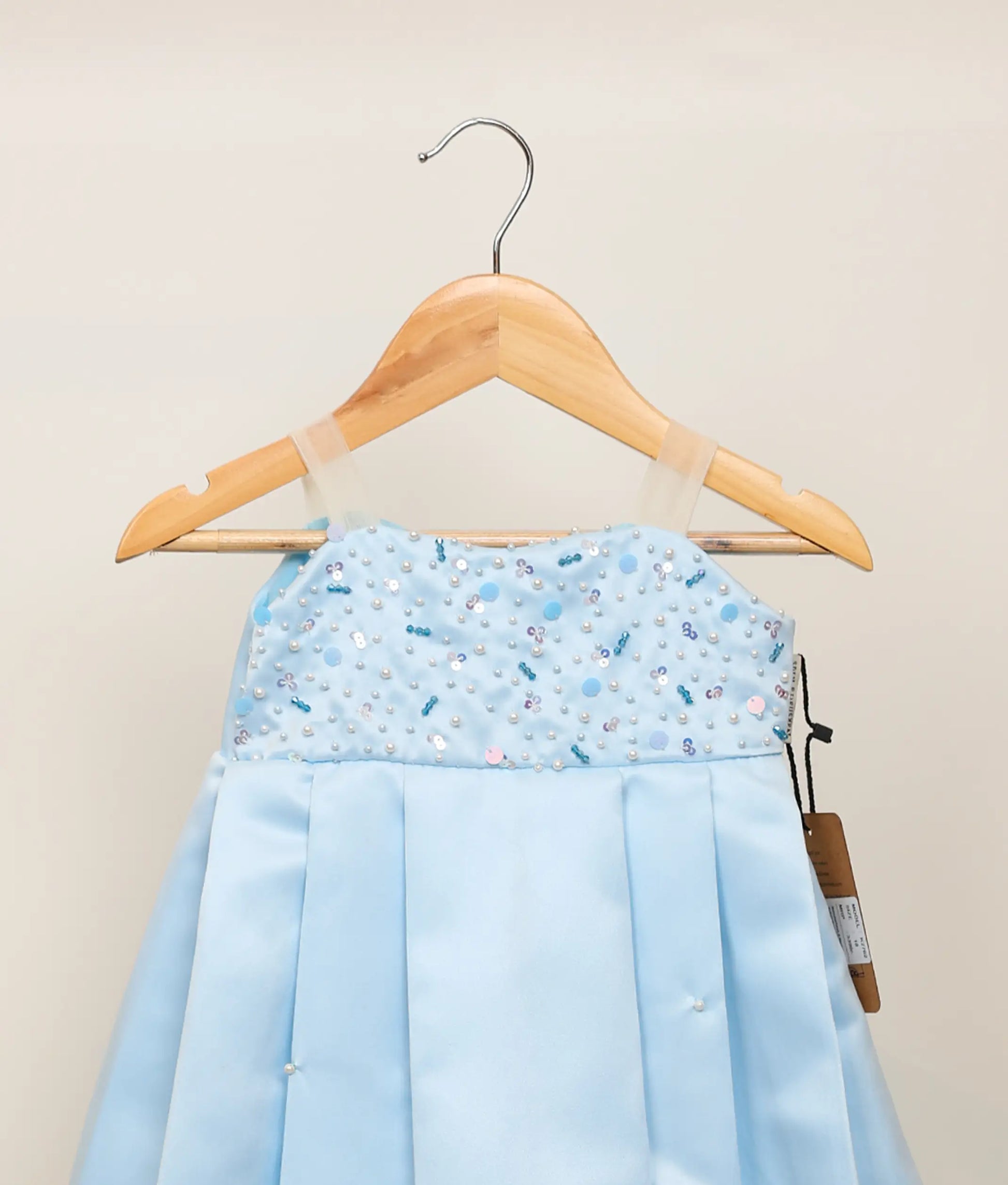 Close view of a handworked satin organza birthday gown against plain background