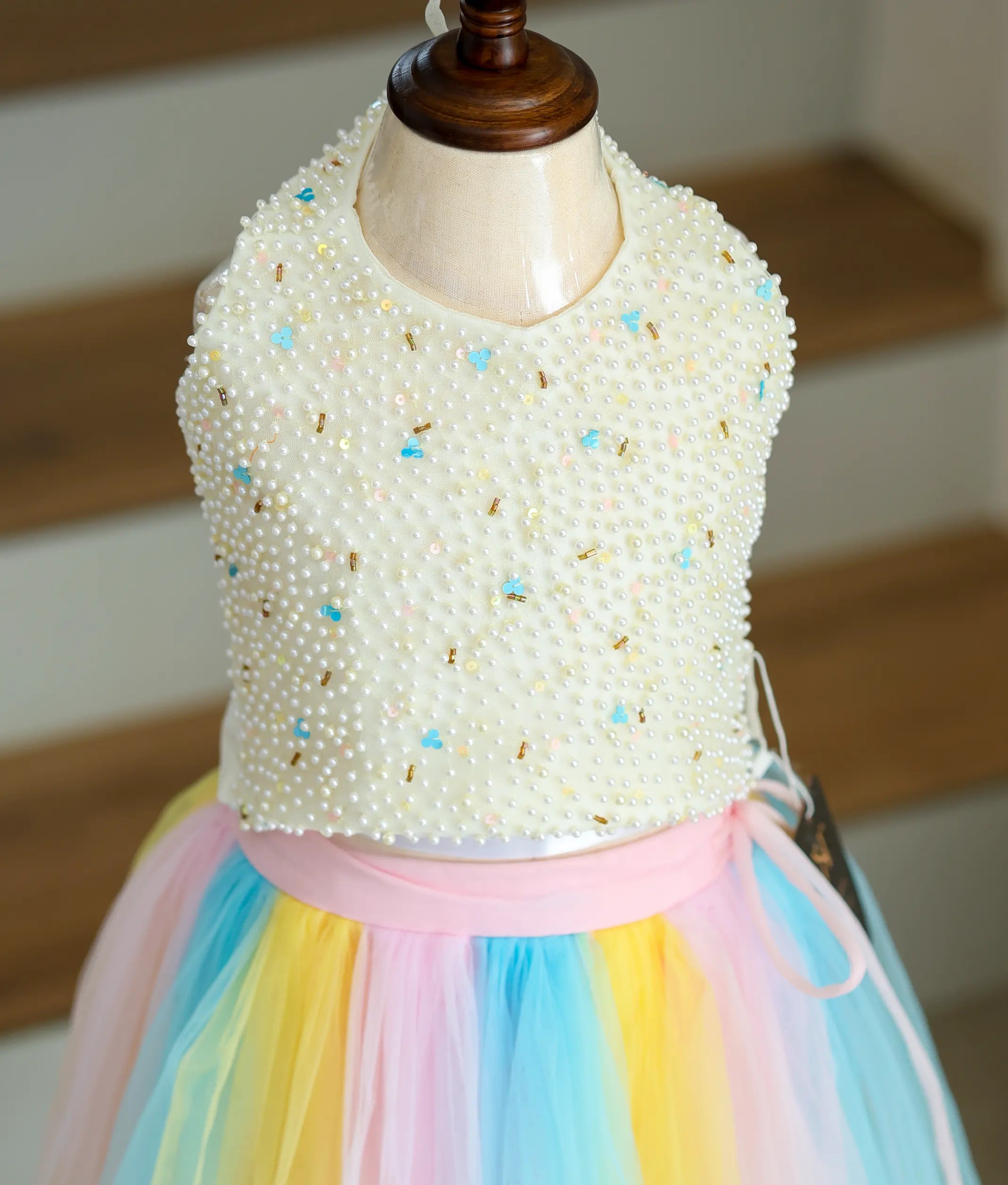 Close view of an off-white top with a multicolor skirt on a mannequin.