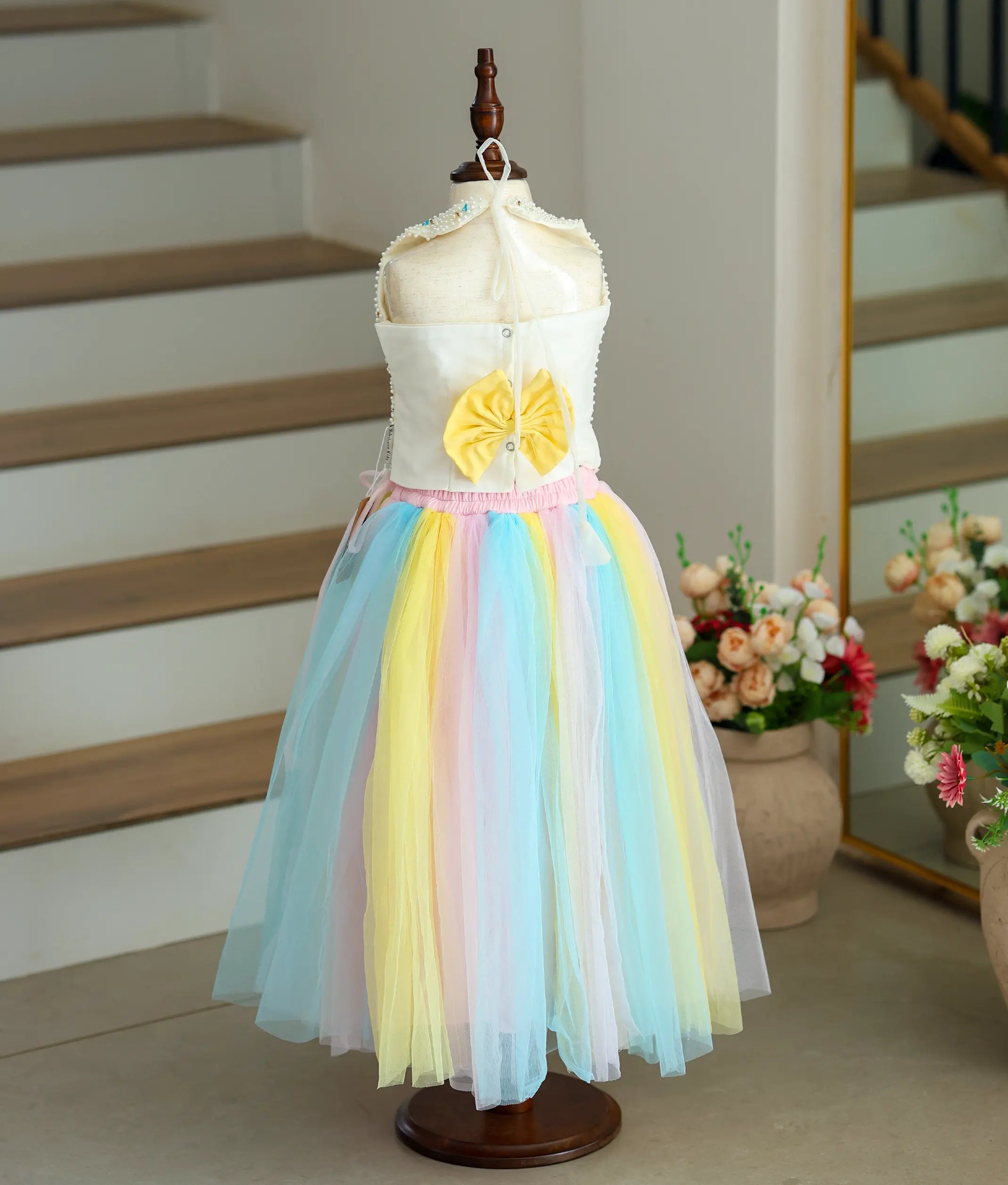 Back view of an off-white top with a multicolor skirt on a mannequin.
