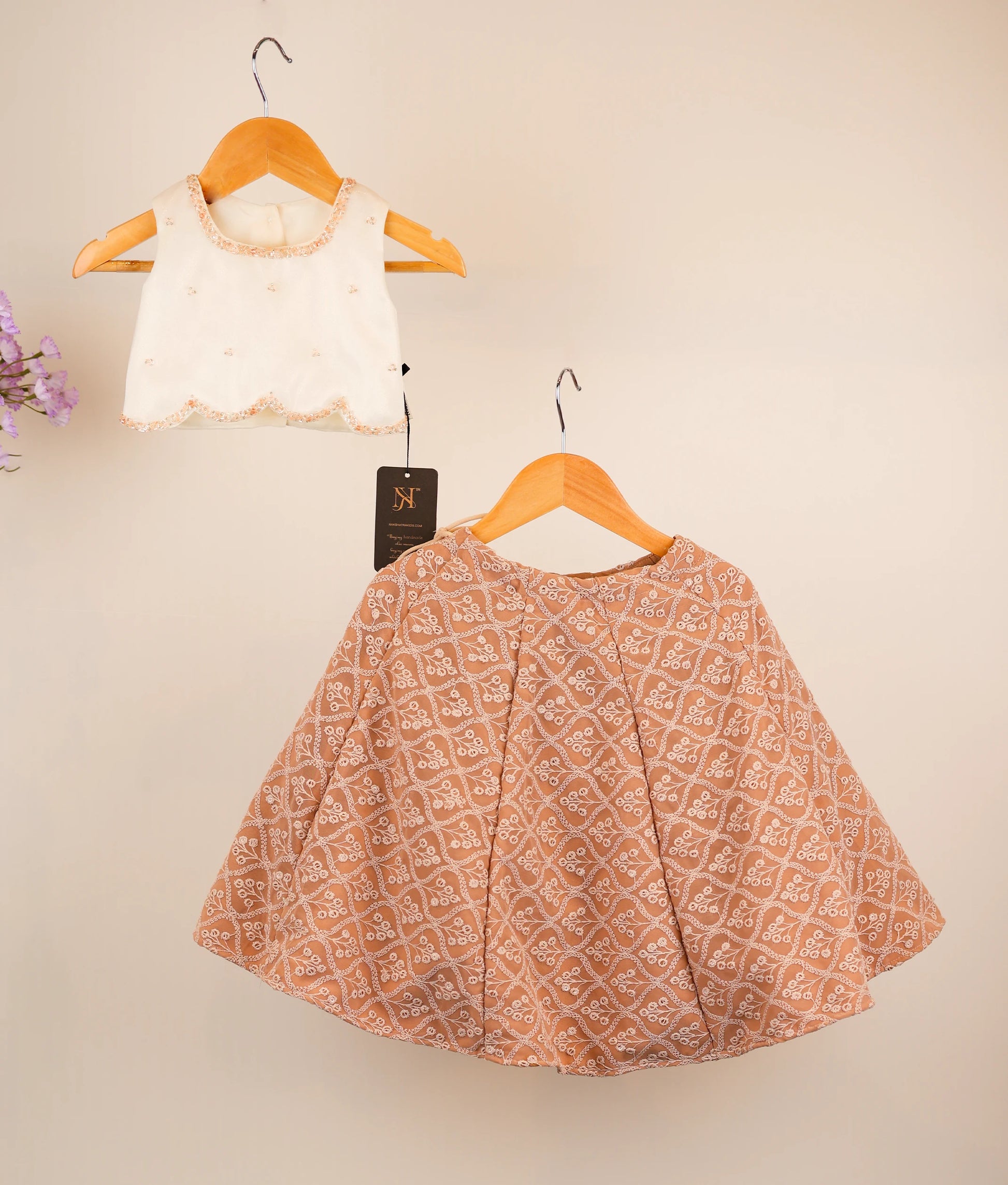 Off-white top and georgette skirt on hangers against a beige background