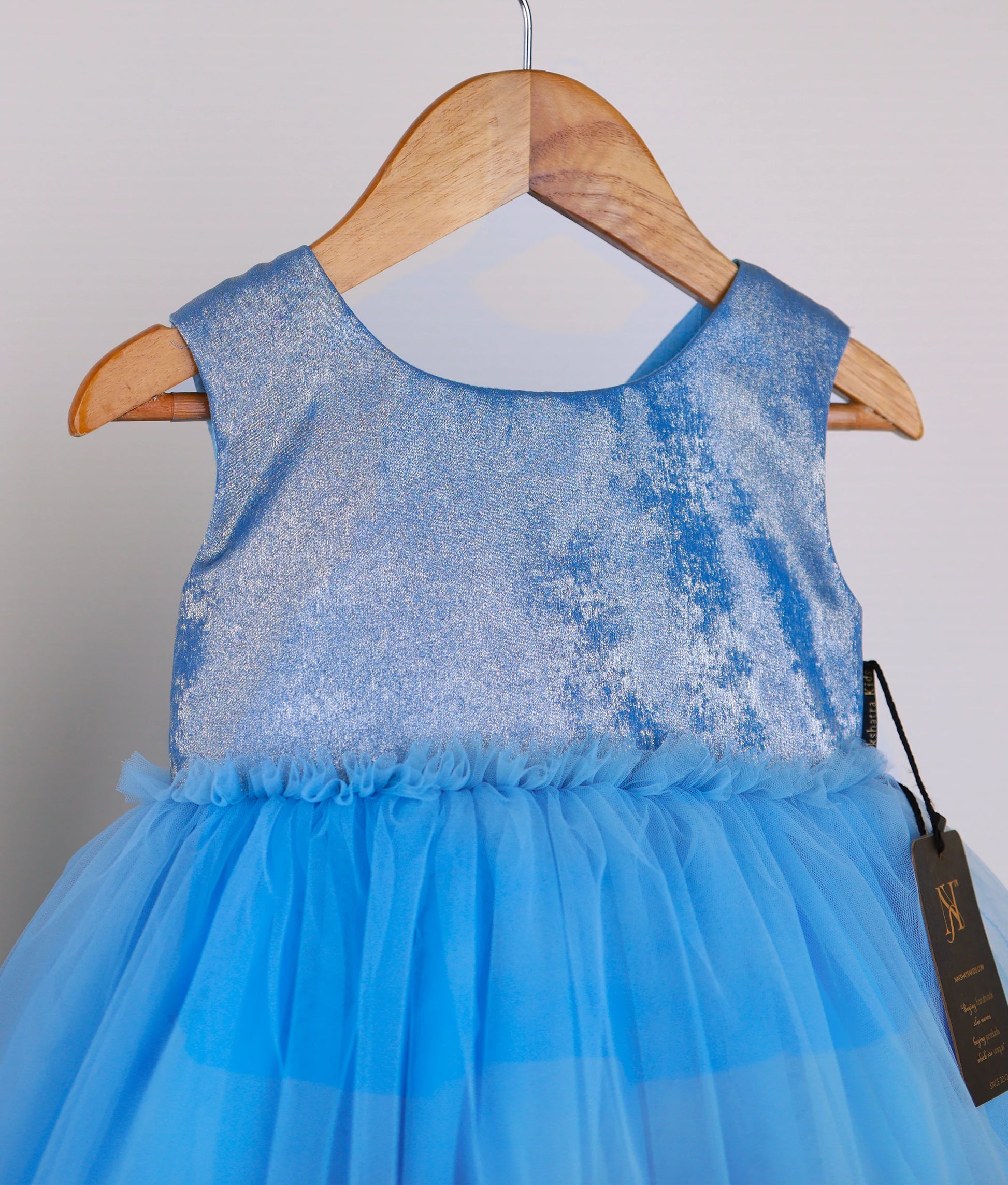 Close view of an pastel blue milan oil tulle net birthday frock against white background