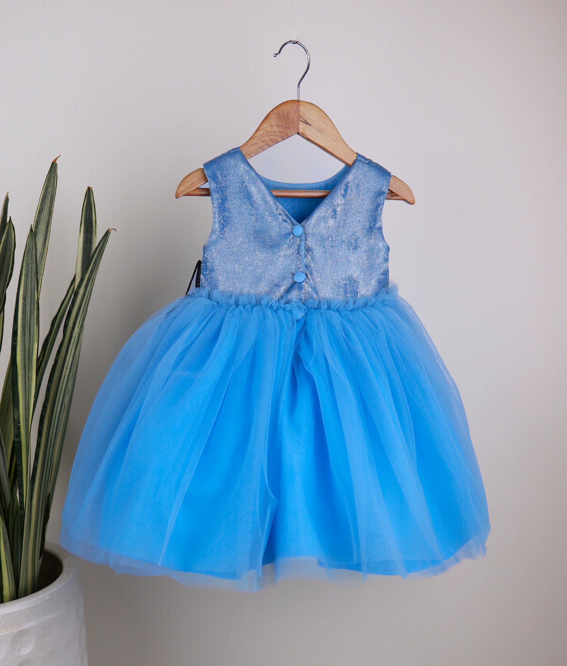 Back view of an pastel blue milan oil tulle net birthday frock against white background