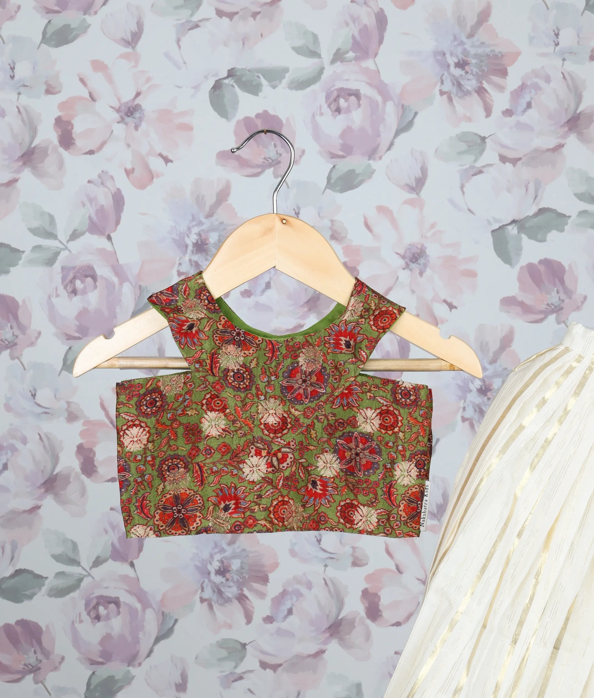 Close view of a olive-green floral print top and an off-white pleated skirt with golden stripes.