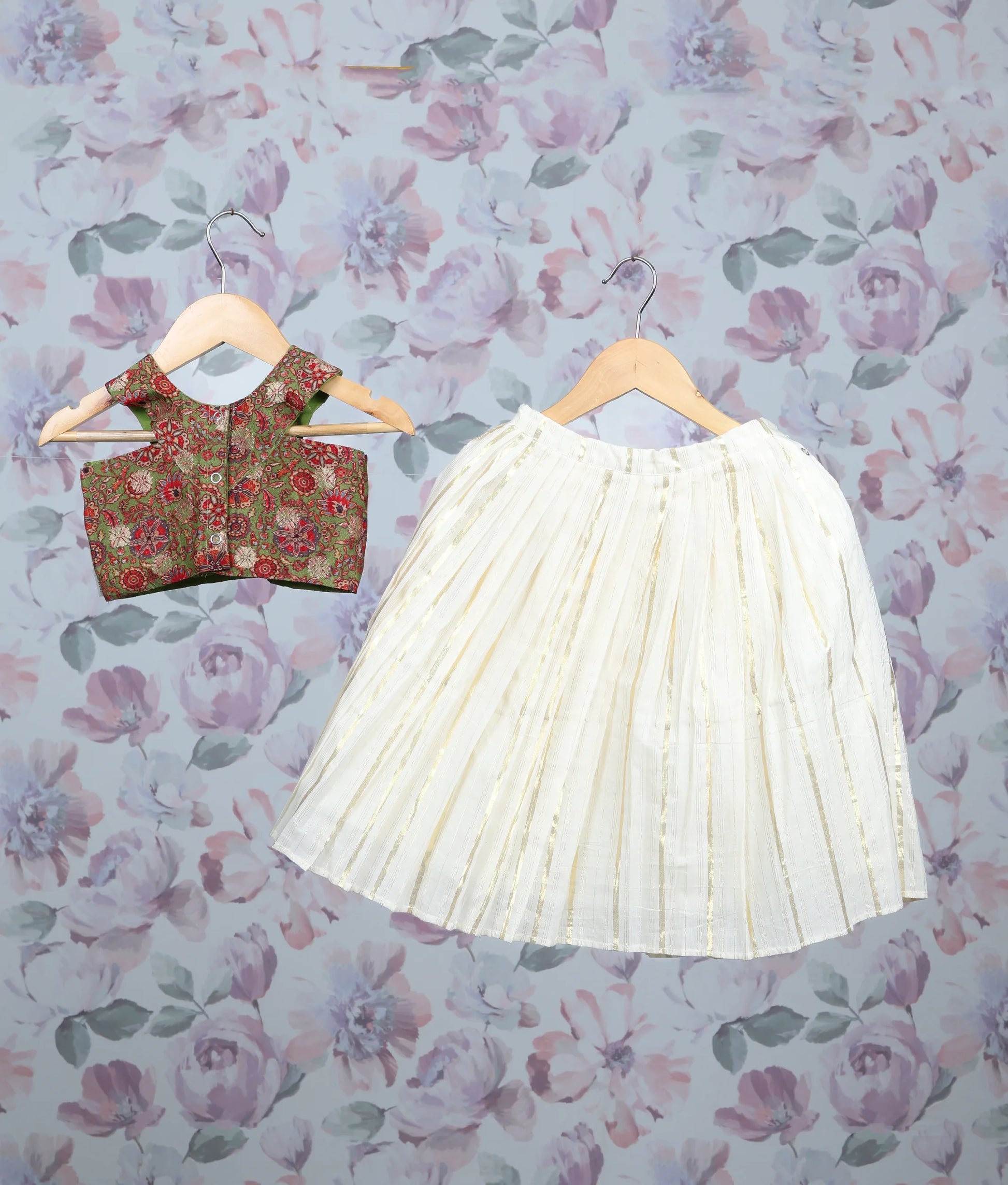 Back view of a olive green floral print top and off-white pleated skirt with golden stripes.