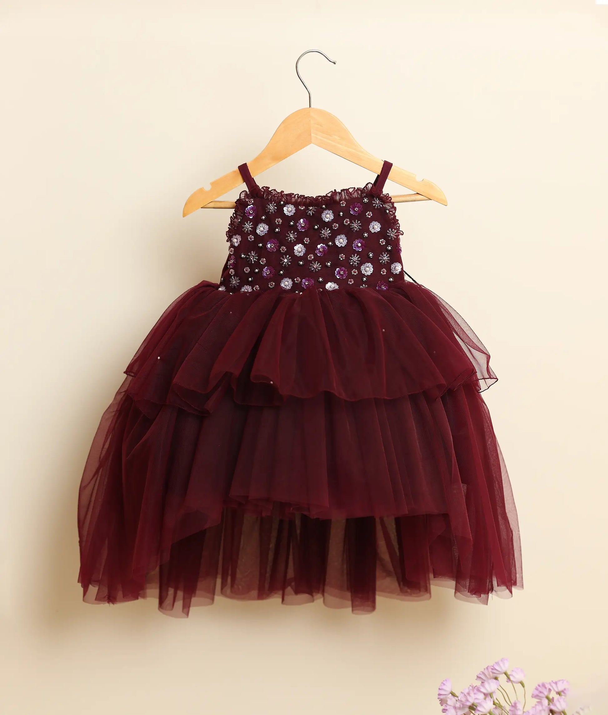 Front view of a wine-red tulle net handworked high-low birthday frock against plain background