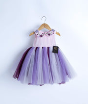 A sleeveless birthday frock hanging on a hanger against a white background.