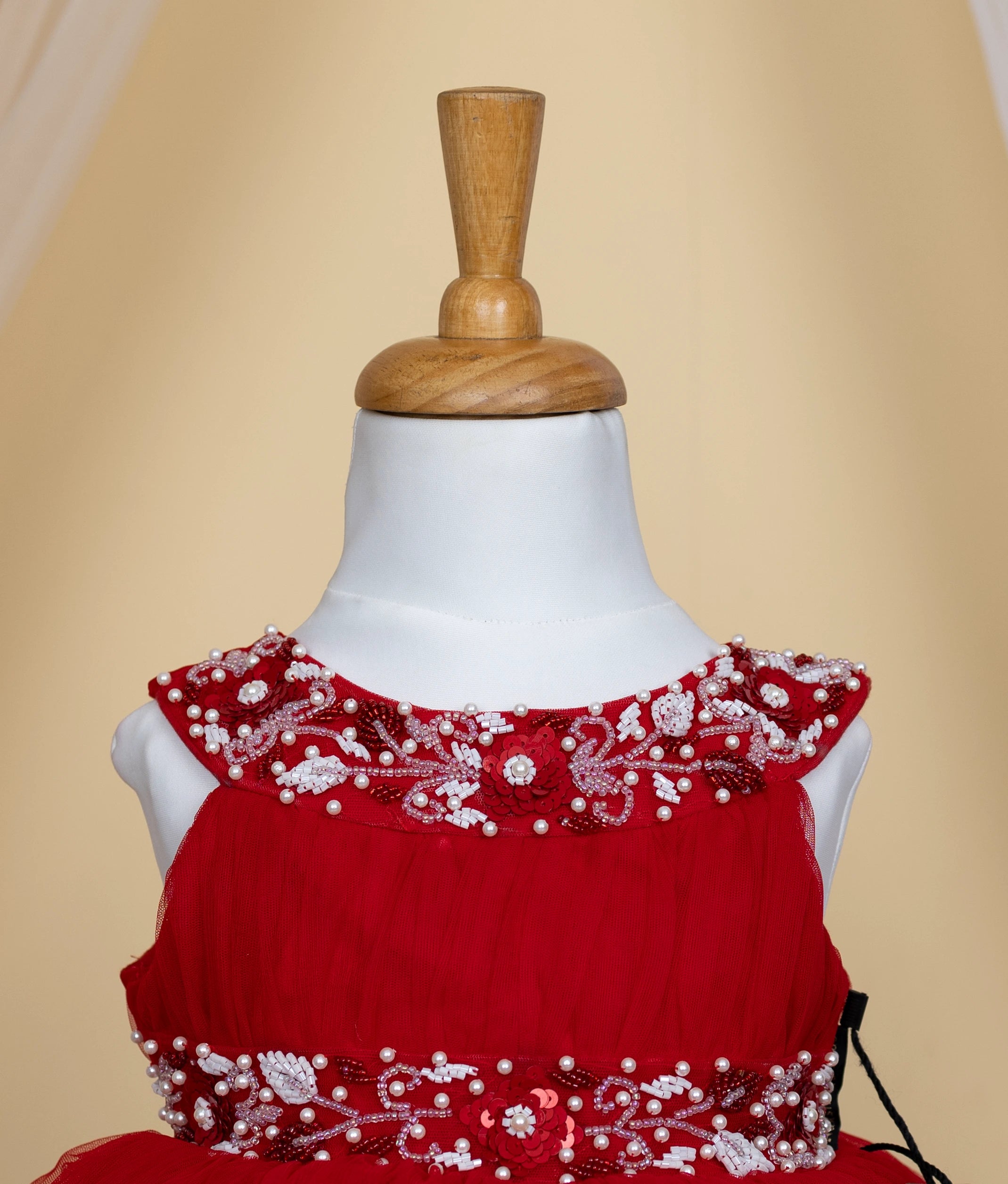 Close view of a red tulle net dress with floral embroidery is displayed on a mannequin.