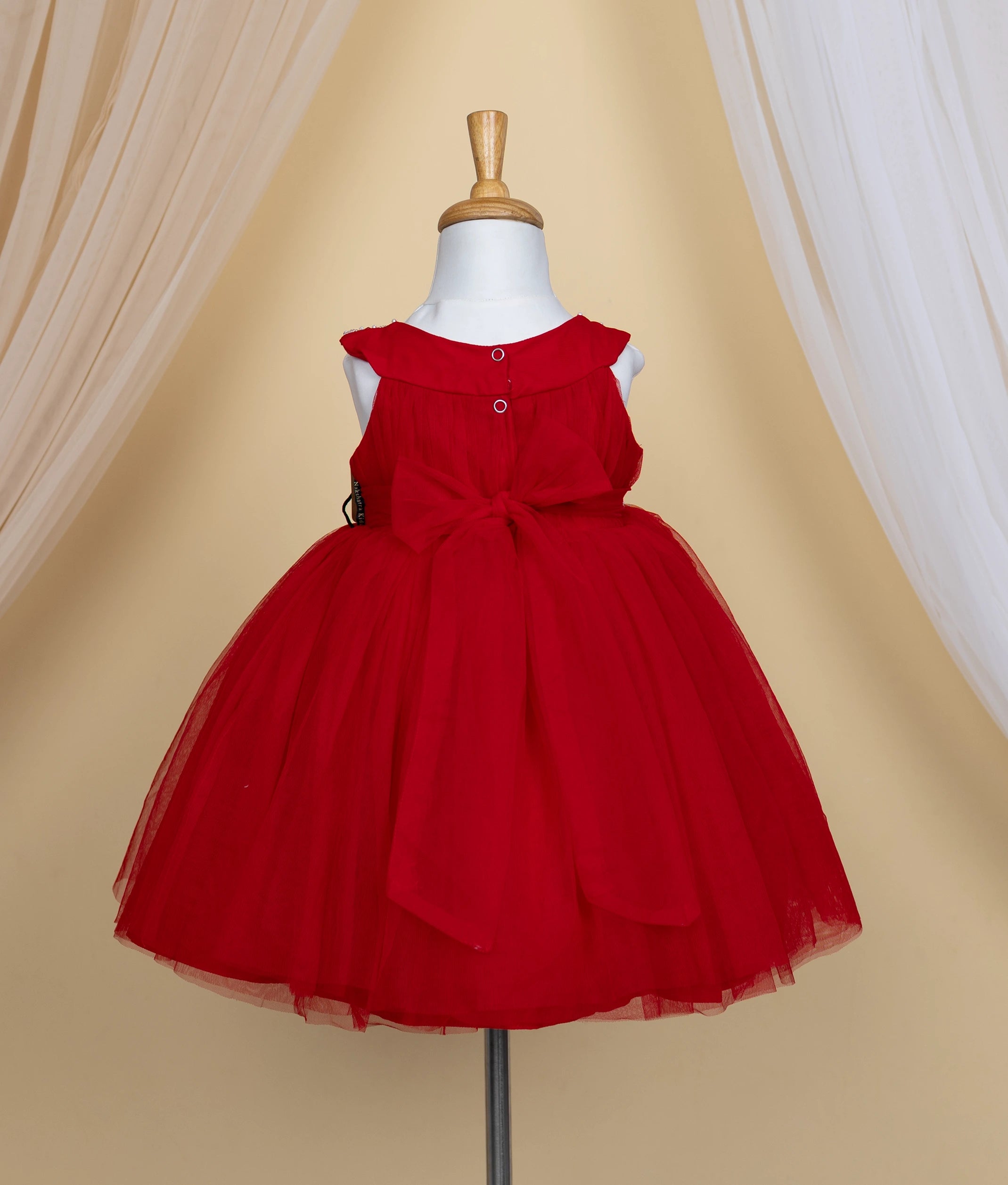 Back view of a red tulle net dress with is displayed on a mannequin.
