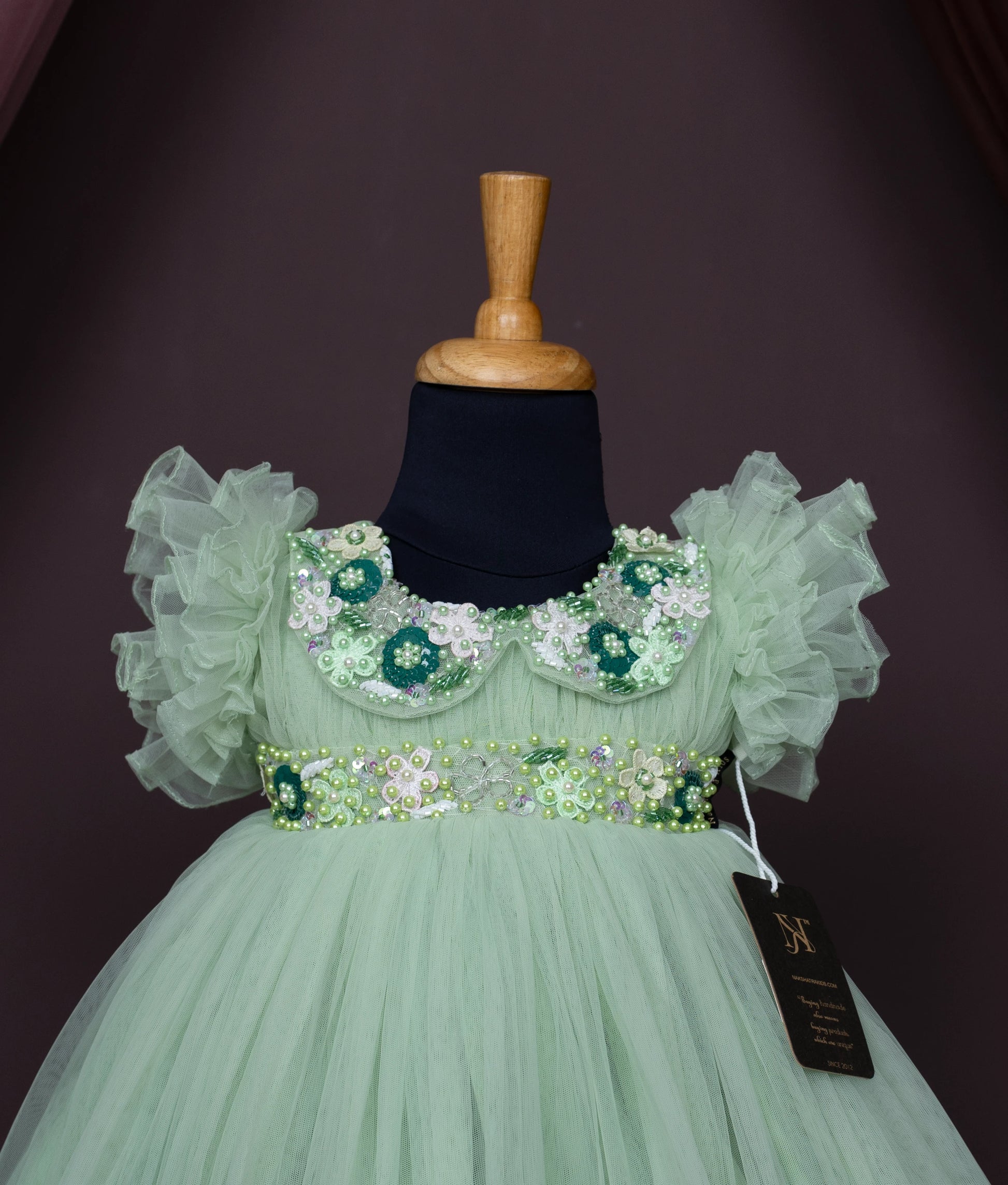 Close view of an pastel green tulle net birthday gown displayed on a mannequin.