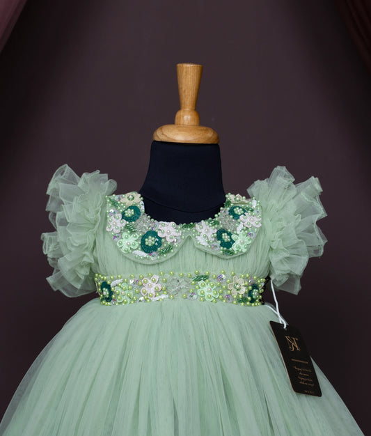 Close view of an pastel green tulle net birthday gown displayed on a mannequin.