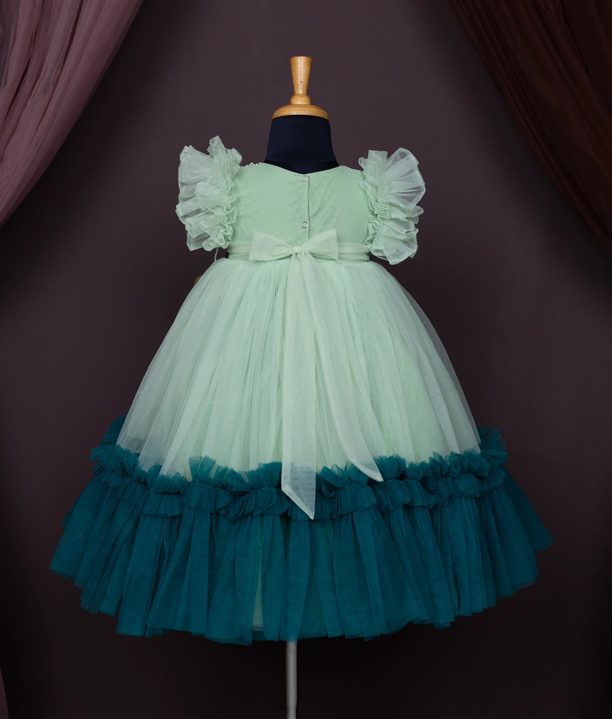 Back view of an pastel green tulle net birthday gown displayed on a mannequin.