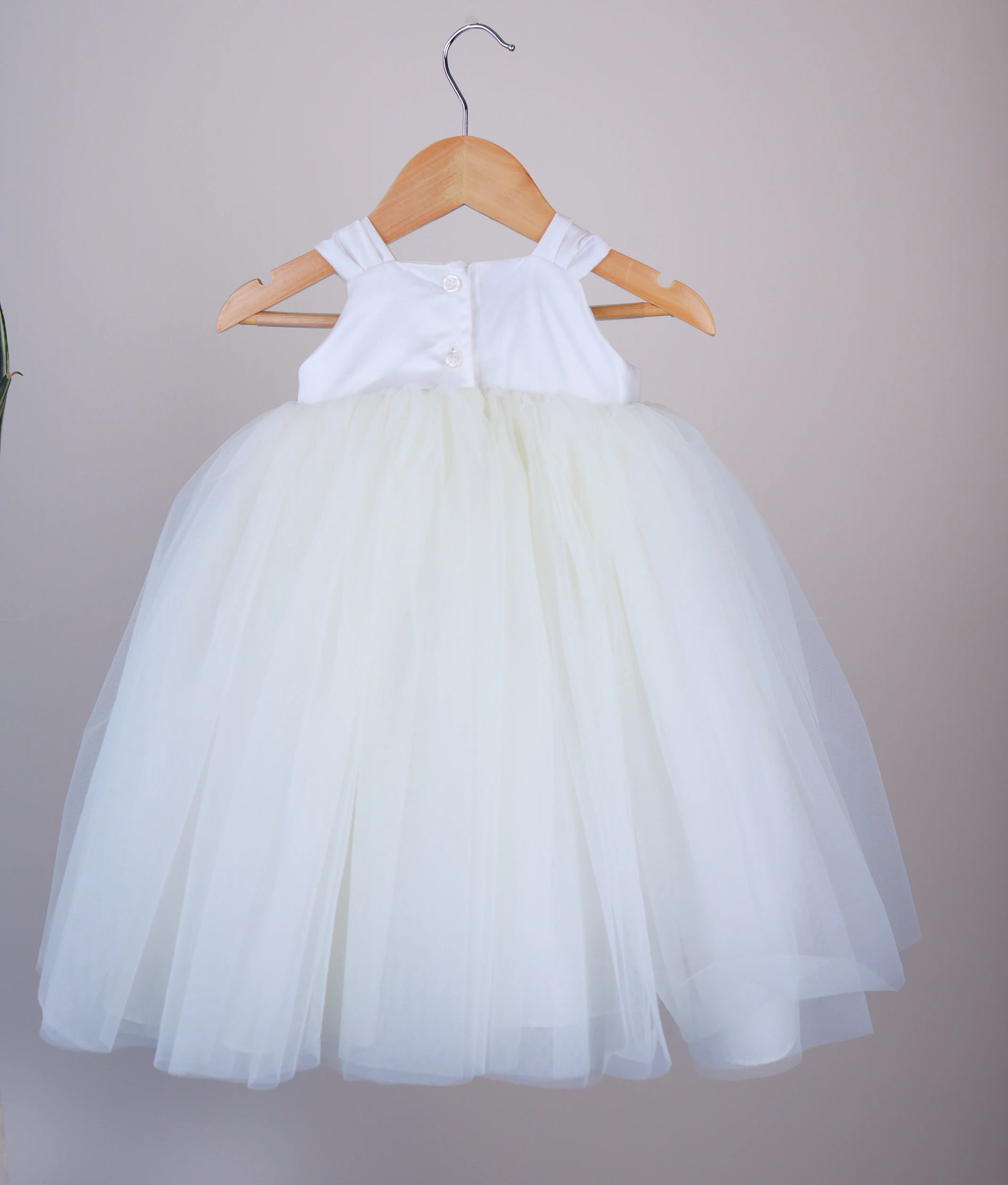 Back view of an off-white tulle net birthday frock against a white background.  