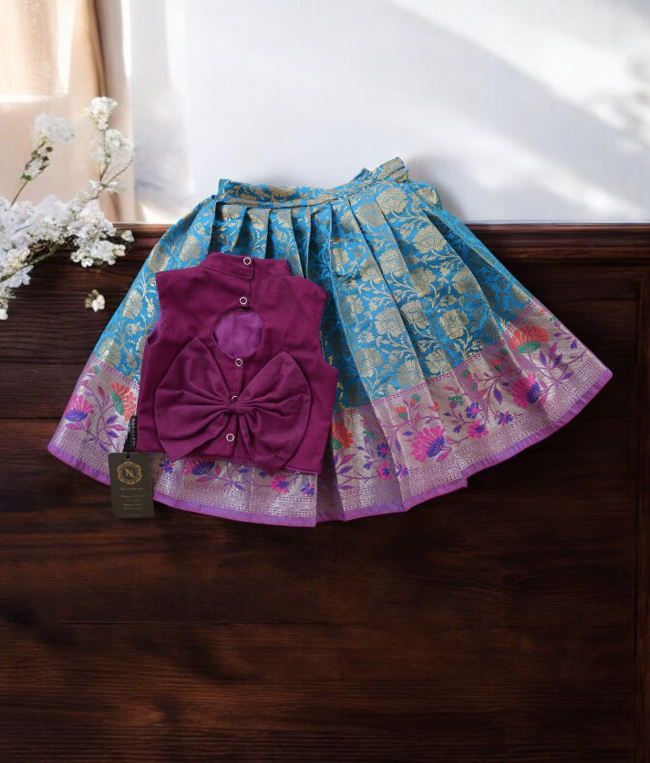 Back view of an grape wine and blue handworked crop top paired with a Banarasi skirt, displayed on a wooden surface.