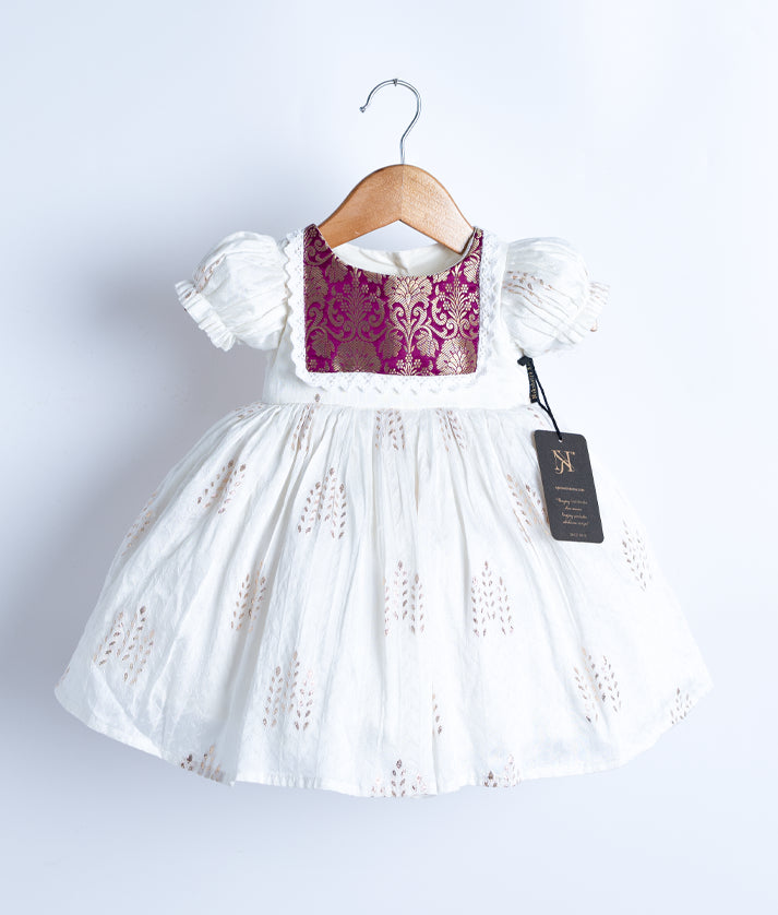 An off-white short-sleeved frock displayed on a hanger.