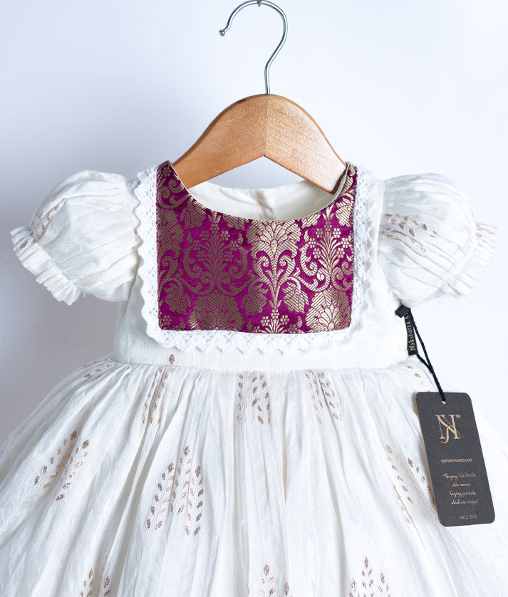 Close view of an off-white short-sleeved frock displayed on a hanger.