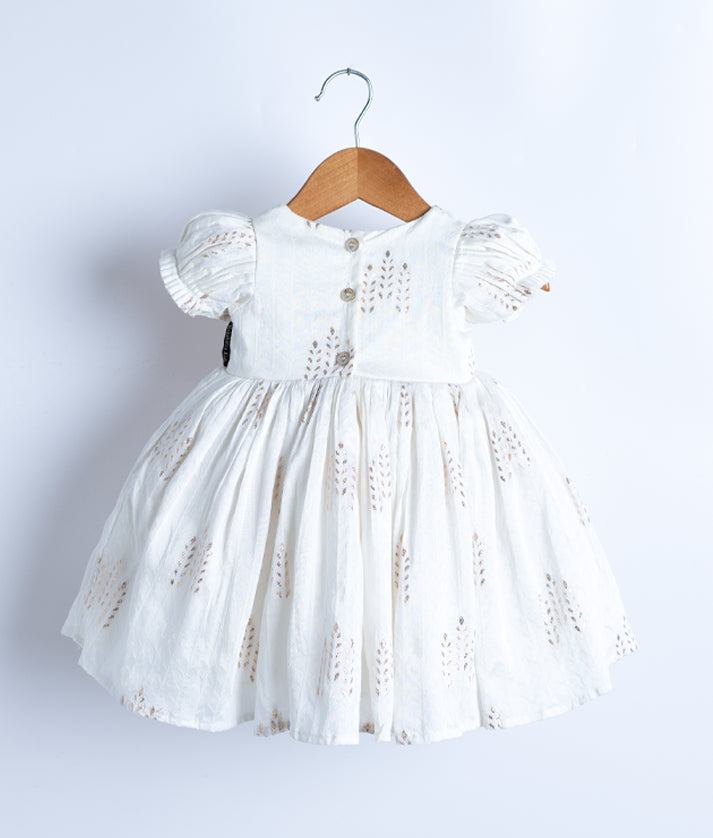 Back view of an off-white short-sleeved frock displayed on a hanger.