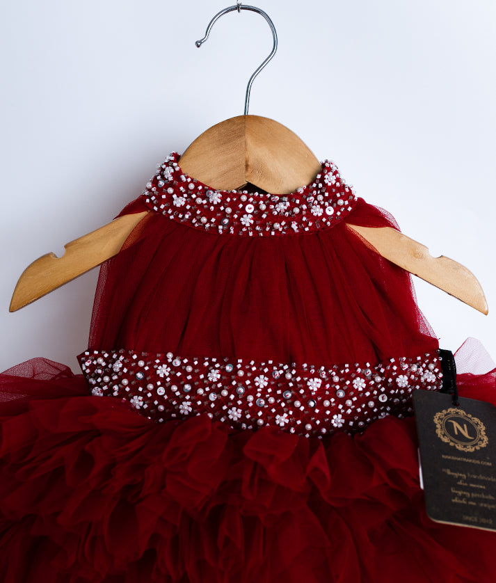Close view of an maroon-colored frock on a wooden hanger.