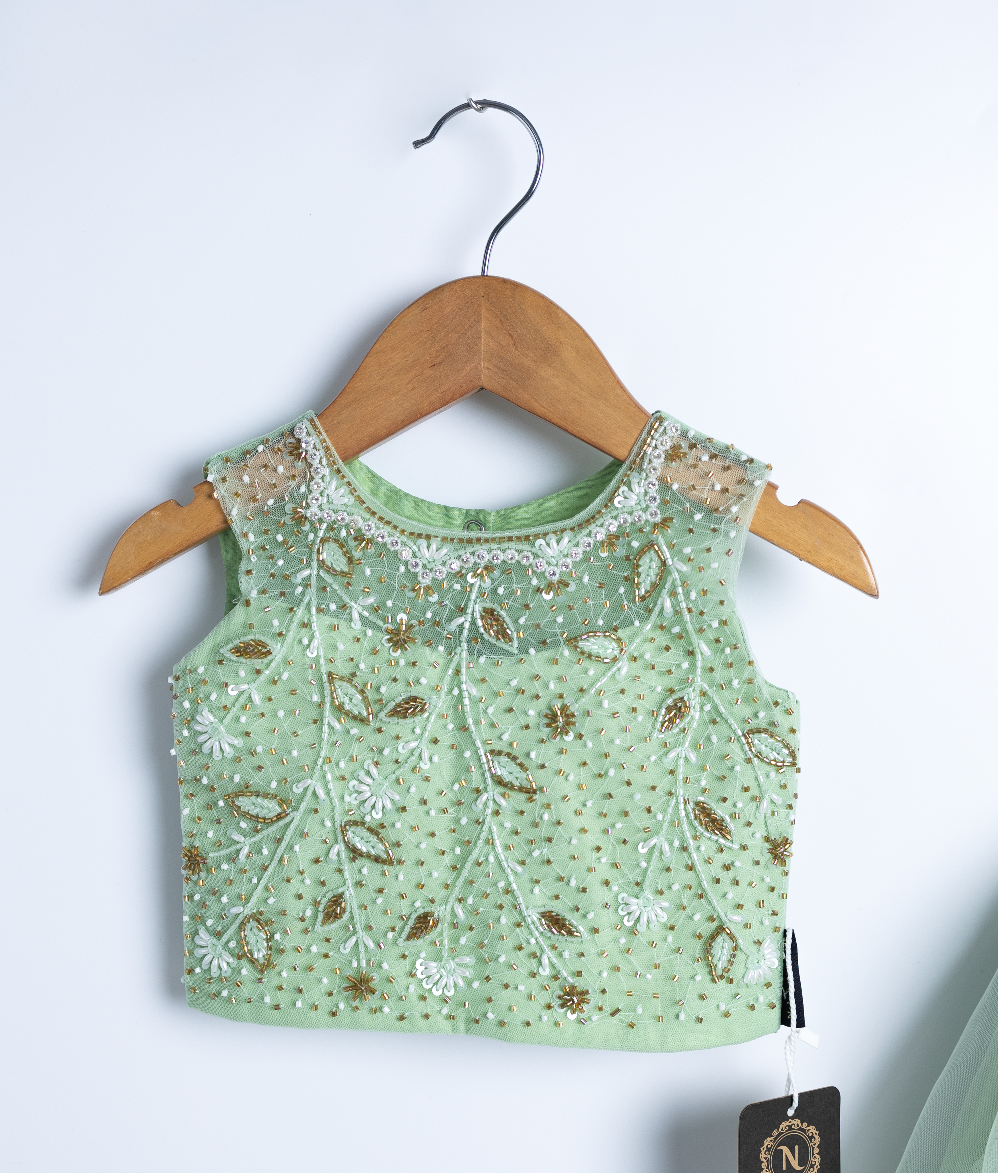 Close view of an pastel green crop top and a skirt displayed on a wooden hangers.