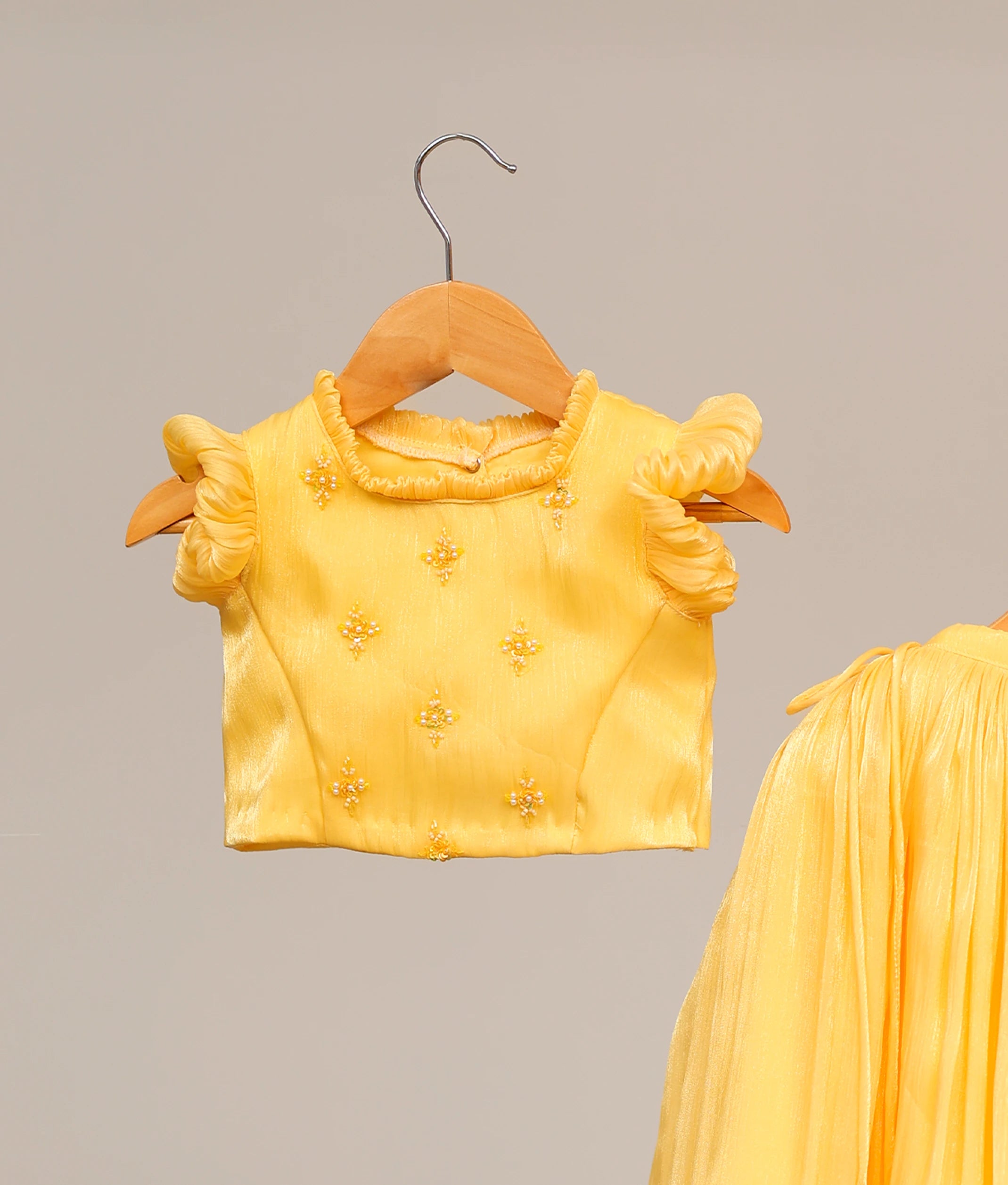Close up view of the yellow top featuring intricate floral handwork embellishments and round neck.