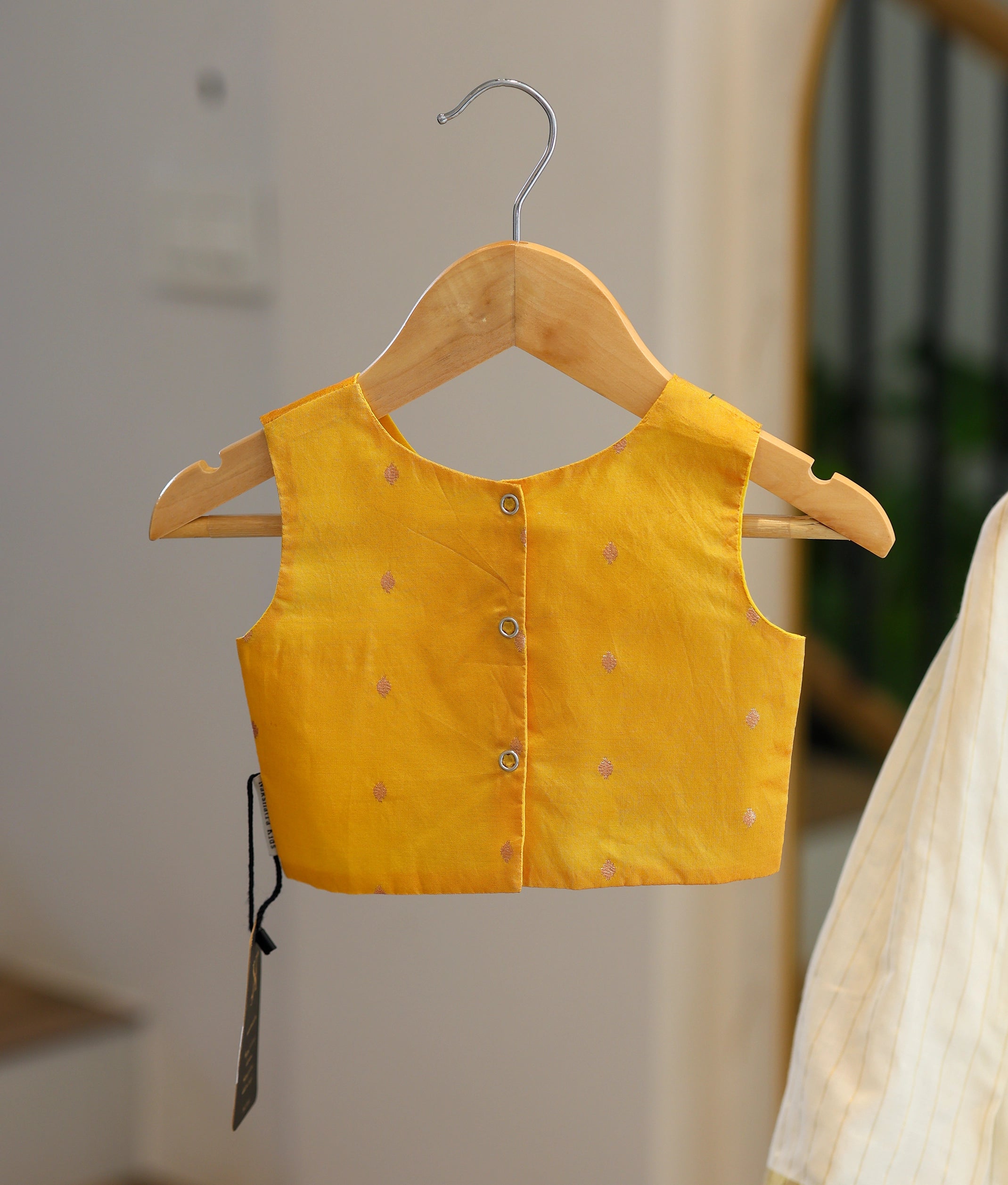 Back view of the yellow top showing the row of secure button closures and clean finish.