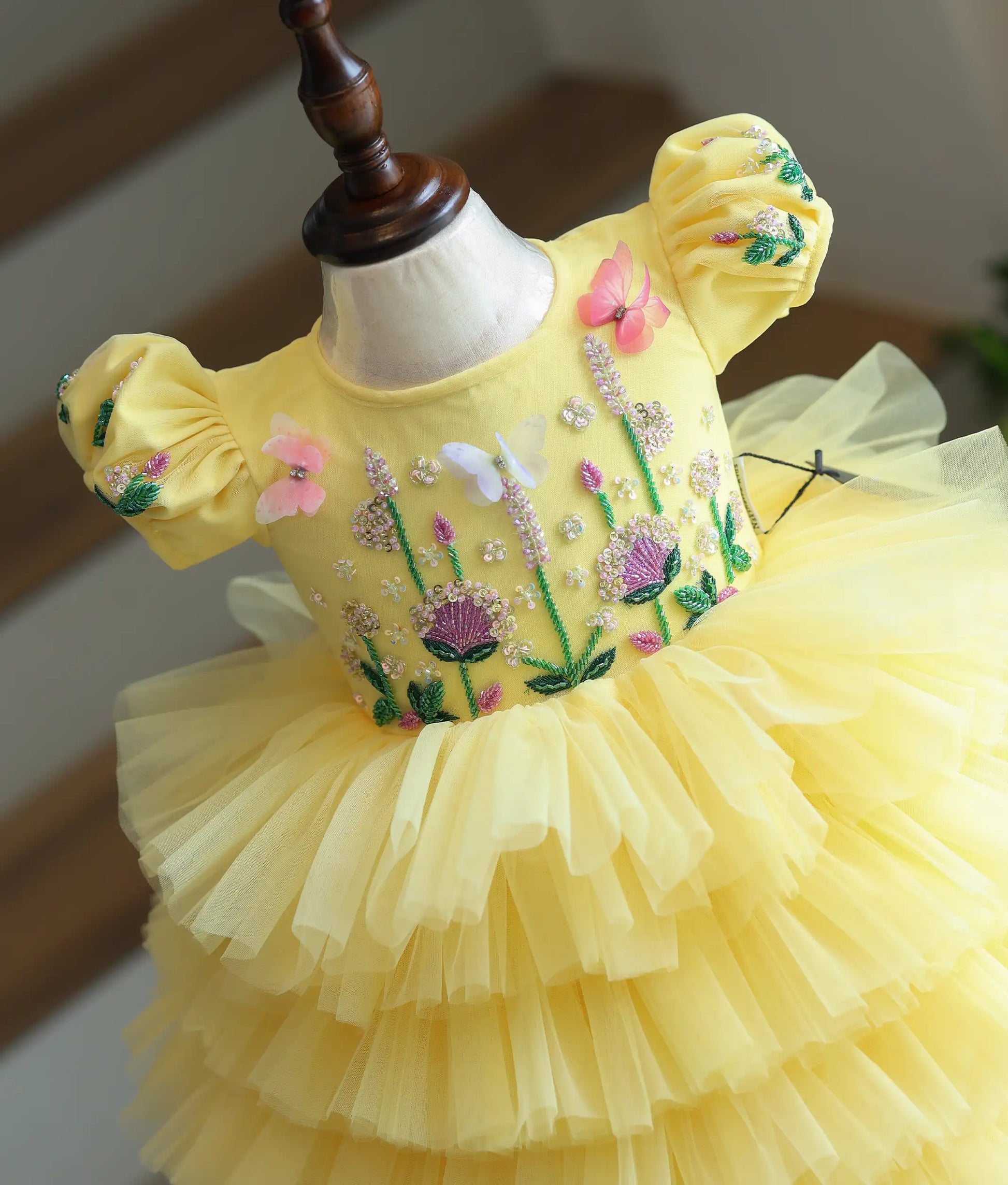 Close-up of butterfly embroidery detail on yellow birthday dress for baby girl