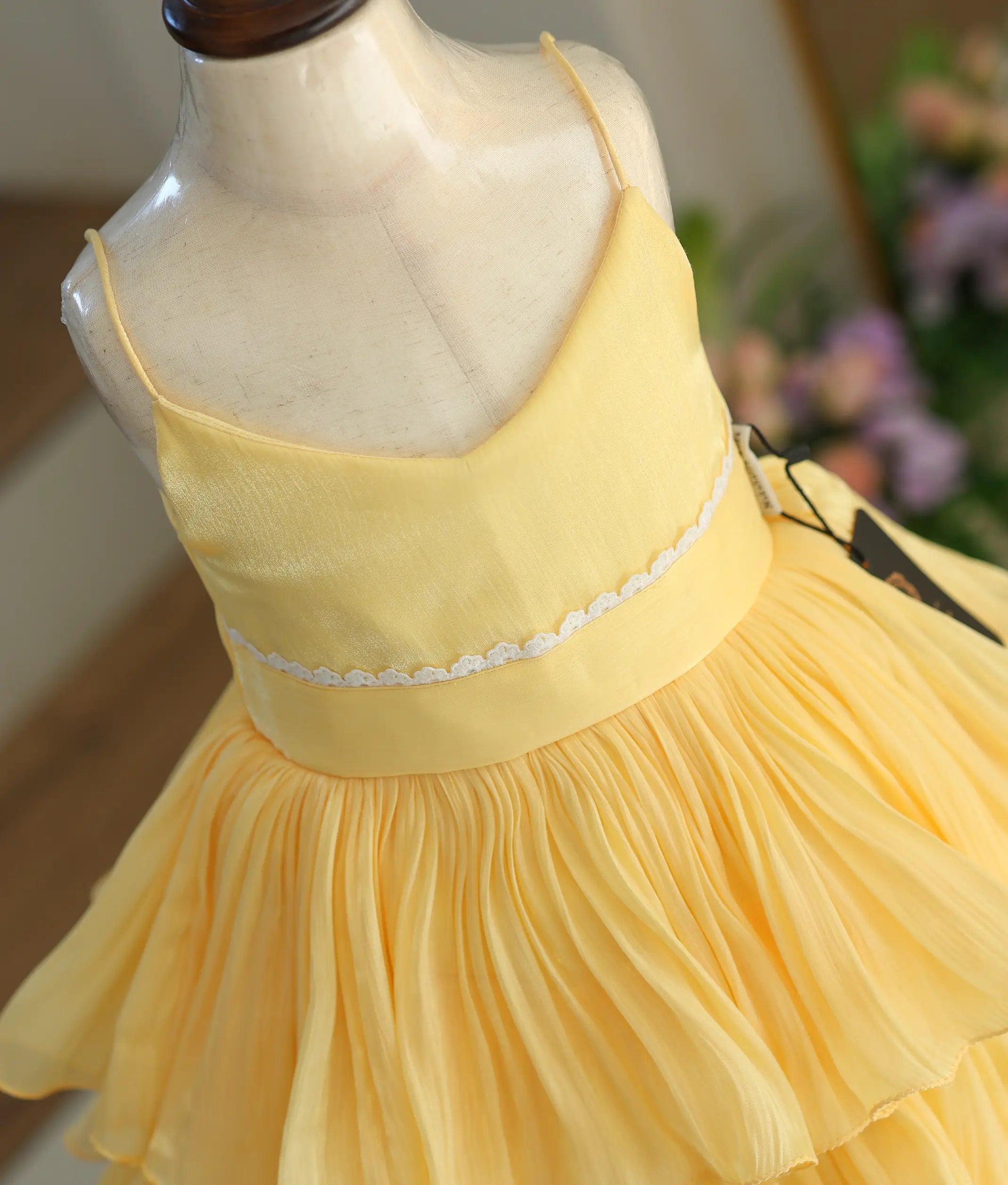 A close-up shot of the yellow frock showing the unique shimmering texture of the laser organza fabric and the lace trim.