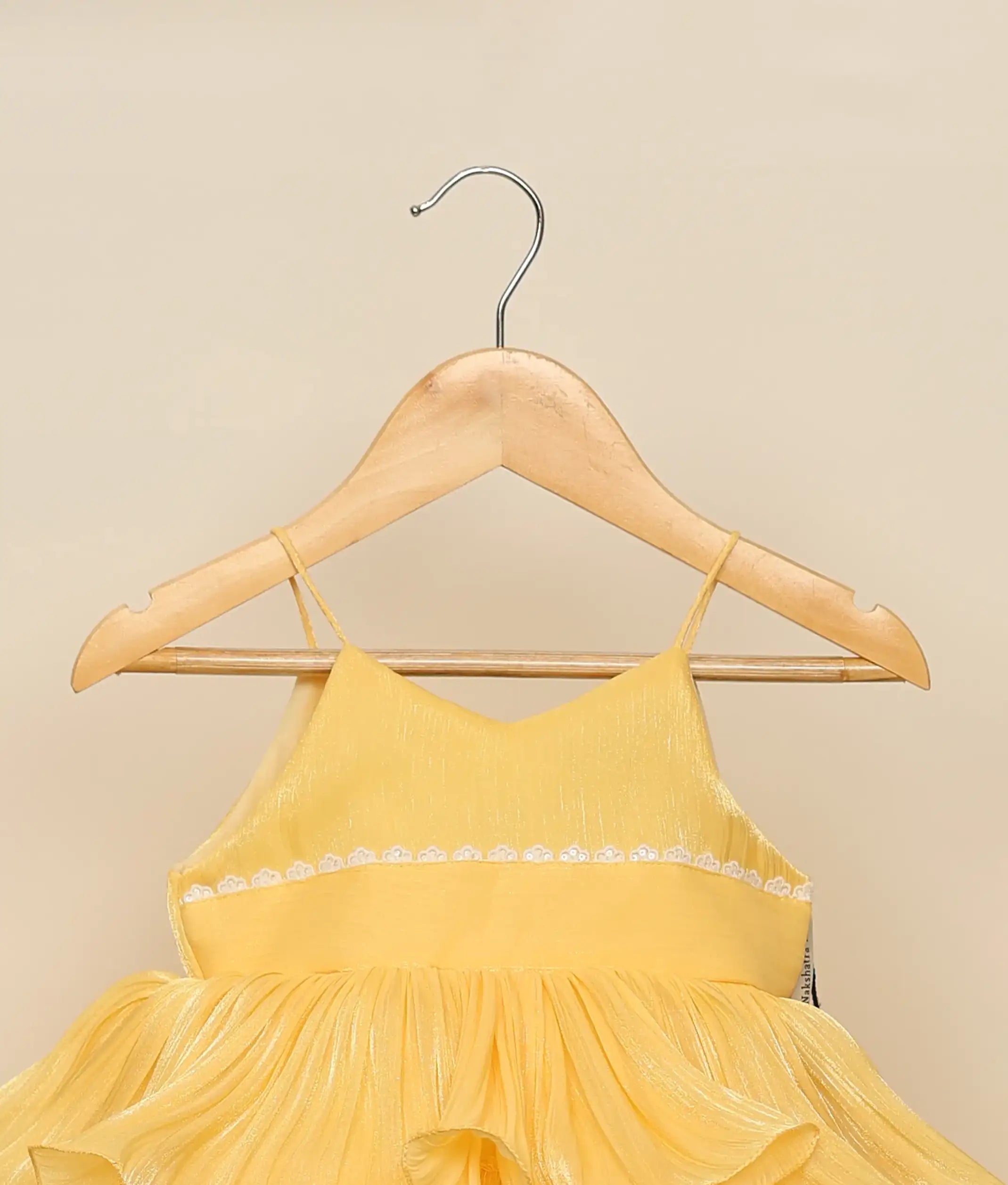 Close-up of the V-neck bodice with white lace detailing and the shimmering pleated texture of the yellow laser organza fabric