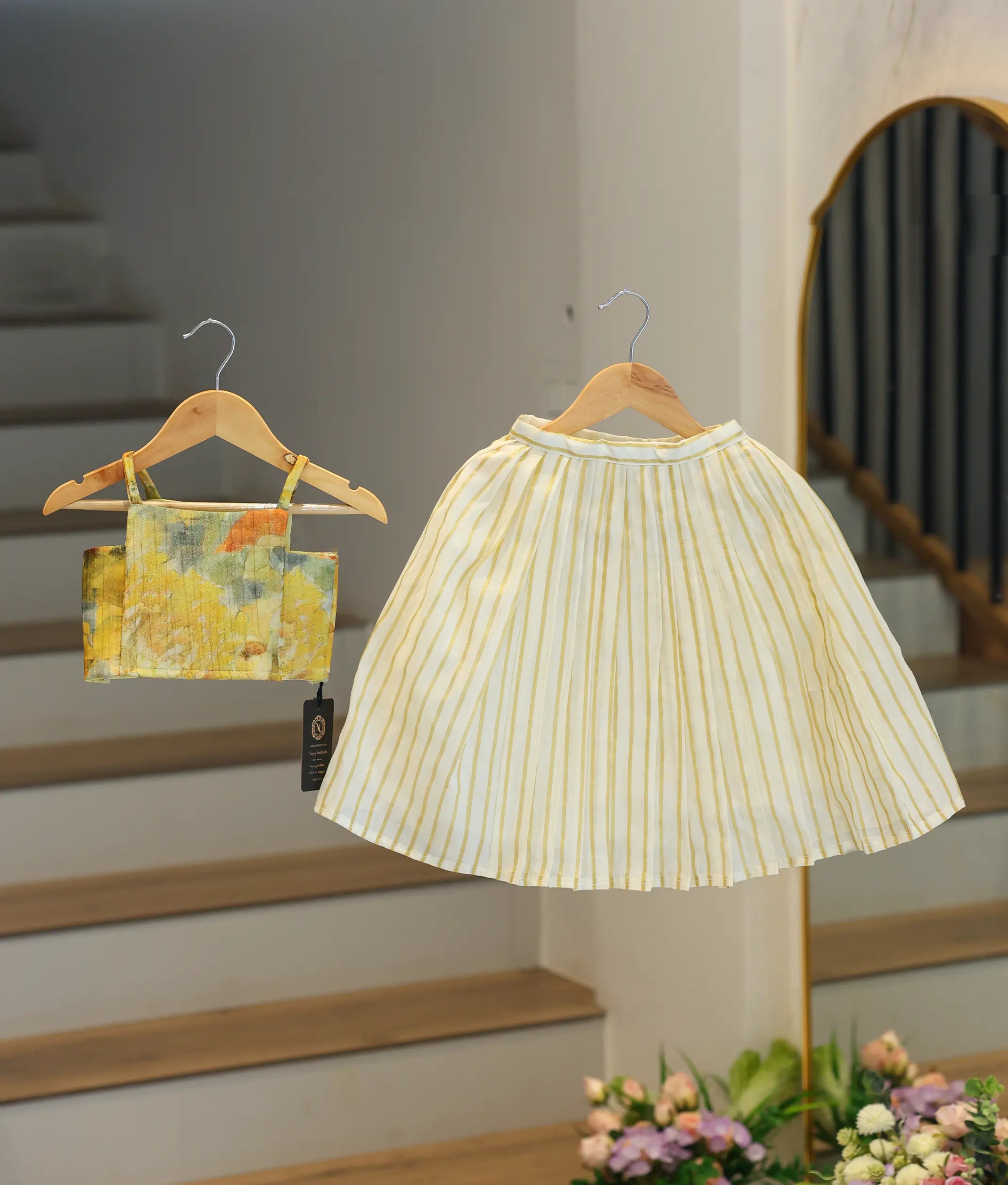 Front view of a girls' ethnic set featuring a yellow floral silk top and a cream skirt with traditional gold kasavu stripes.