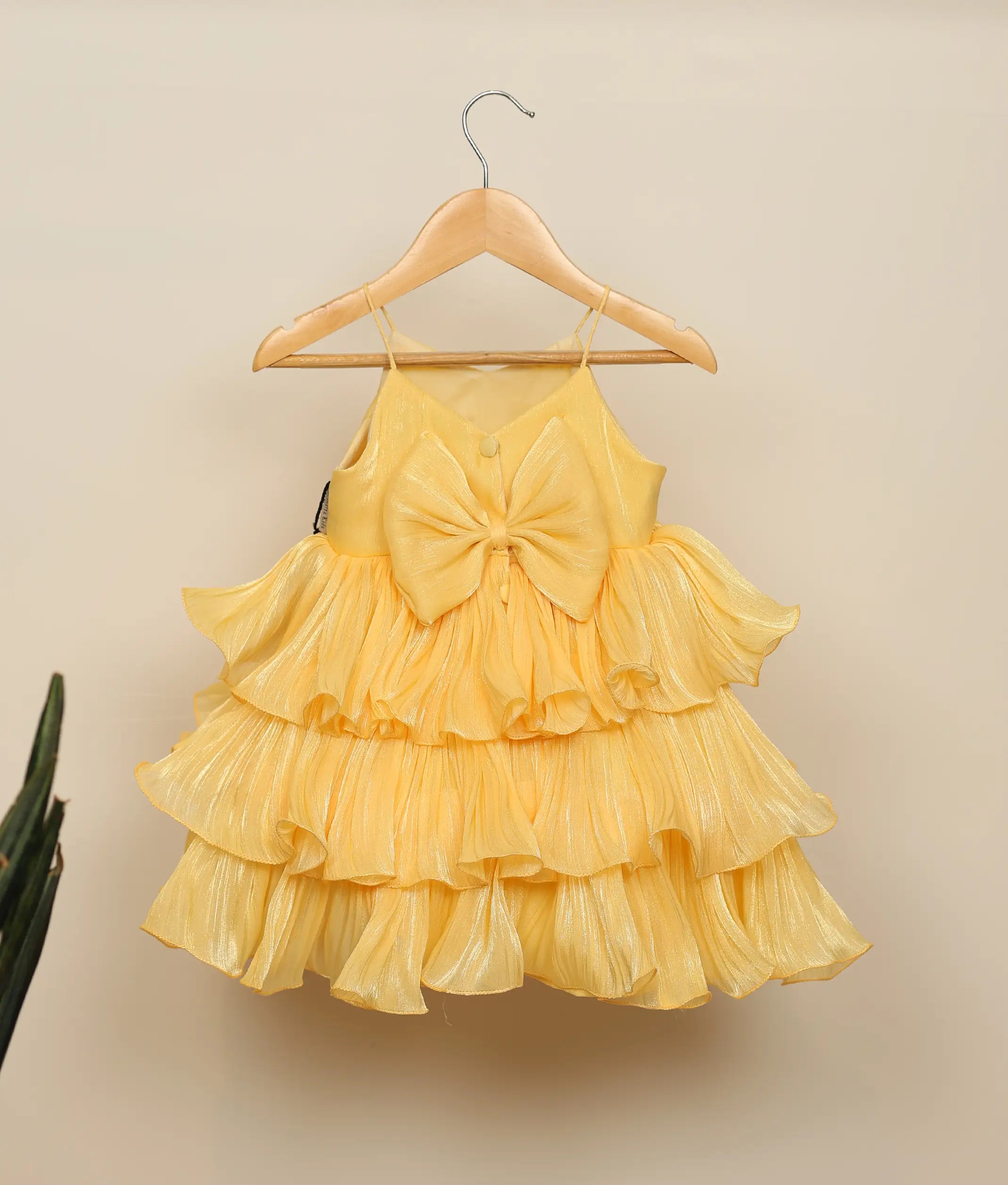 Back view of yellow birthday dress showing the V-neck back closure with show button and tiered organza layers